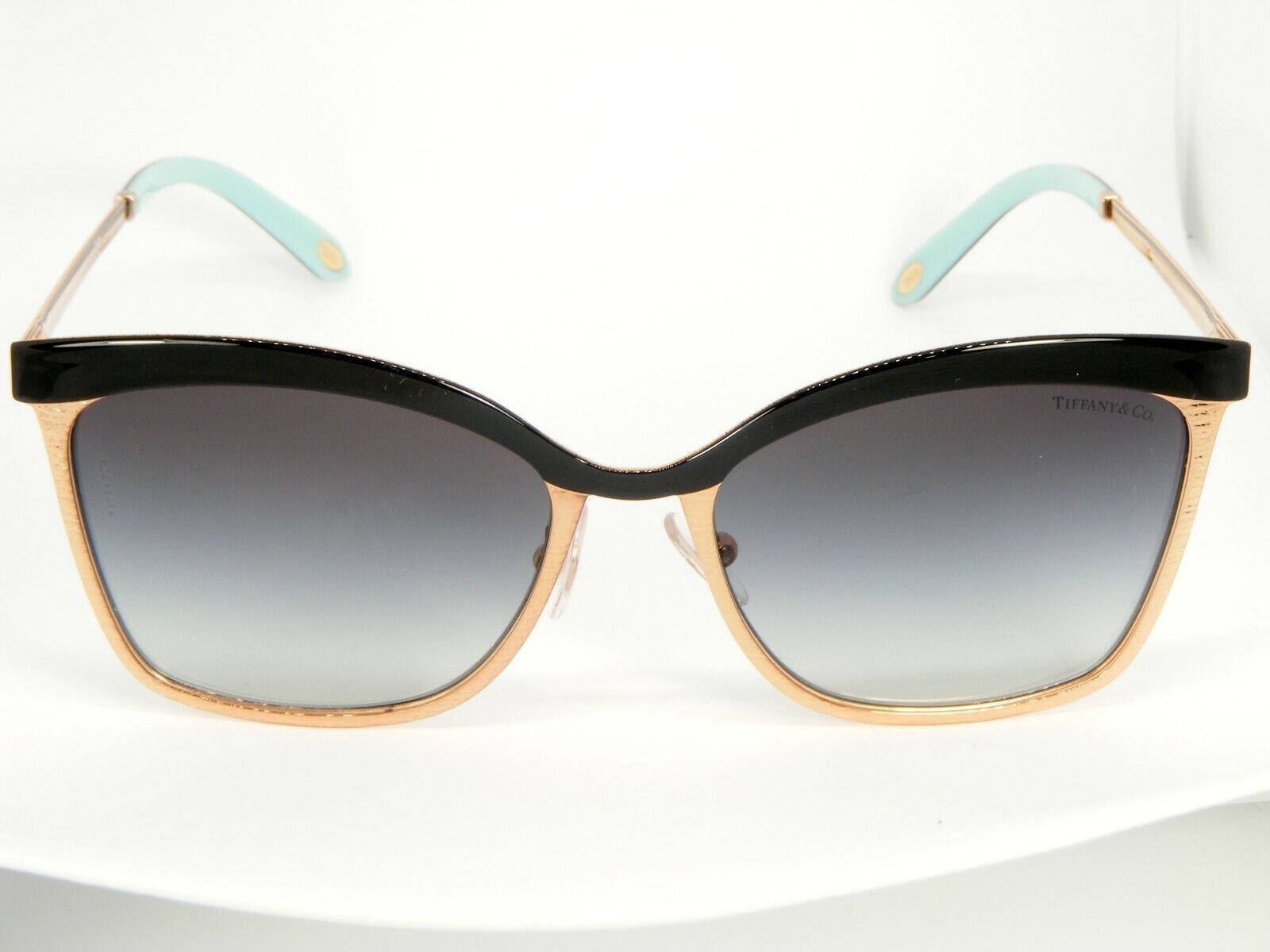 Sunglasses 桌布 壁紙 — 優雅的貓眼太陽眼鏡，黑色頂框、金色側邊和薄荷綠色鏡腿尖端，展示在白色表面上。