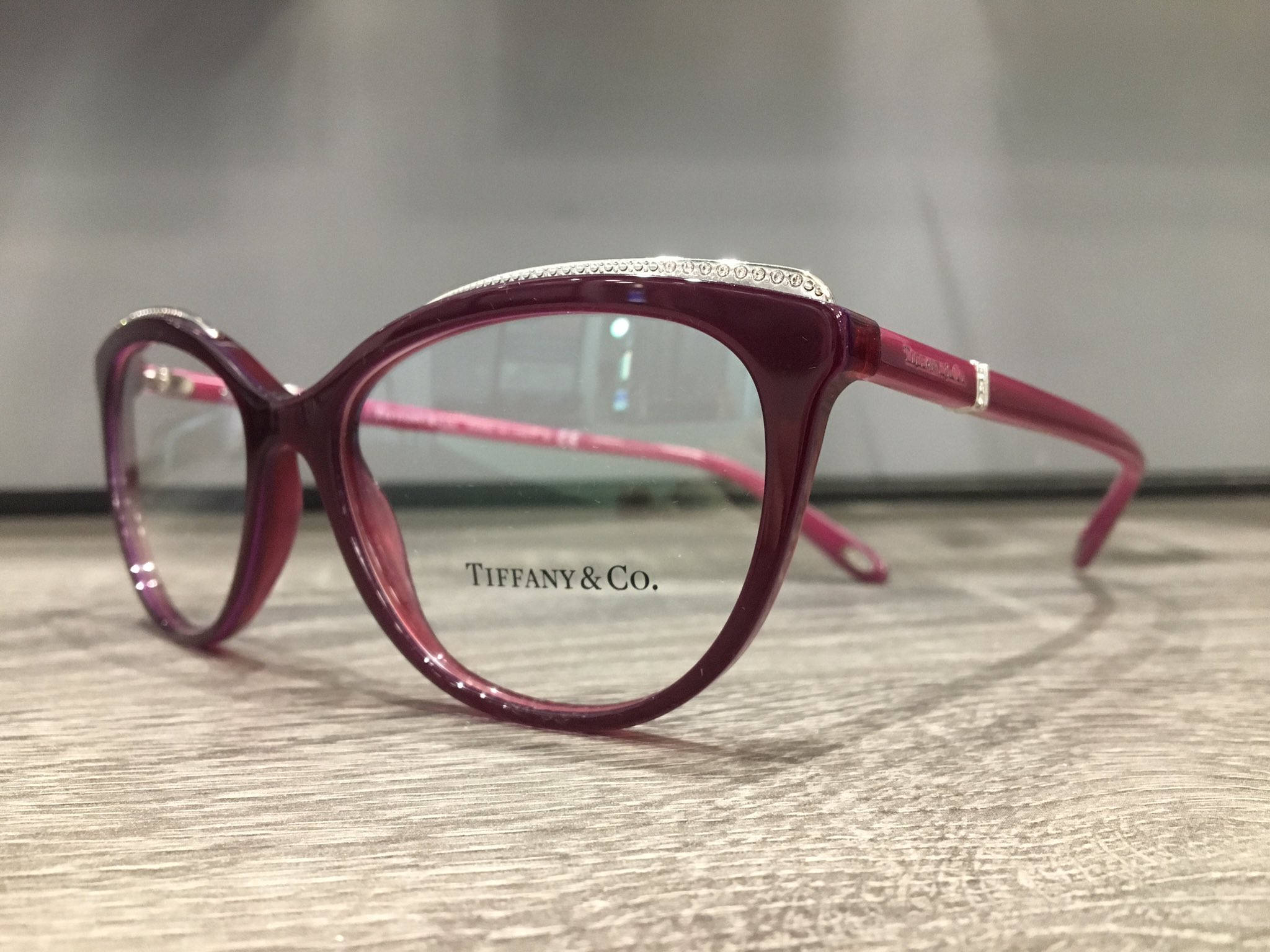 品牌 桌布 壁紙 — 優雅的酒紅色Tiffany & Co.眼鏡，帶有銀色裝飾，放置在紋理木質表面上。