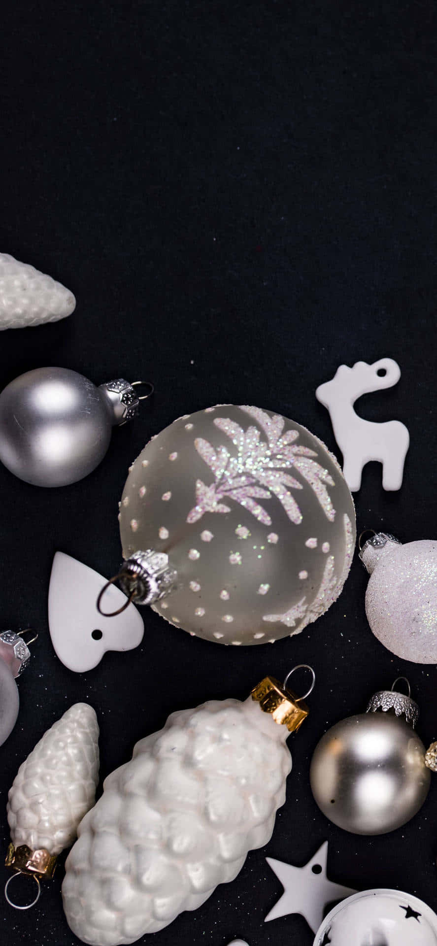 Ornaments 桌布 壁紙 — 優雅的銀色和白色聖誕裝飾品和松果排列在深色背景上。