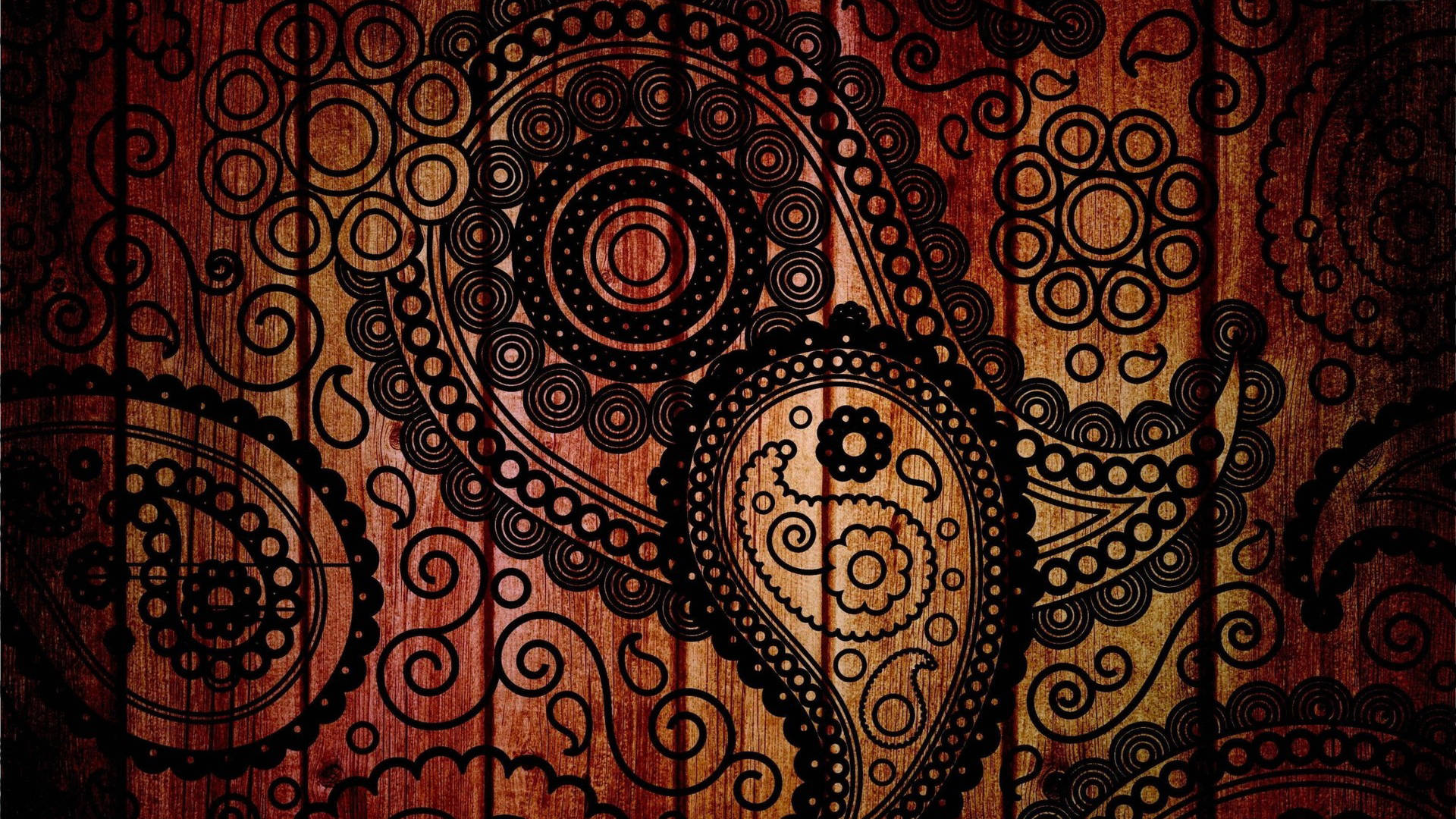 Paisley 桌布 壁紙 — 優雅的黑色佩斯利圖案在豐富紋理的木質表面上旋轉，帶有溫暖的琥珀色和深紅色調。