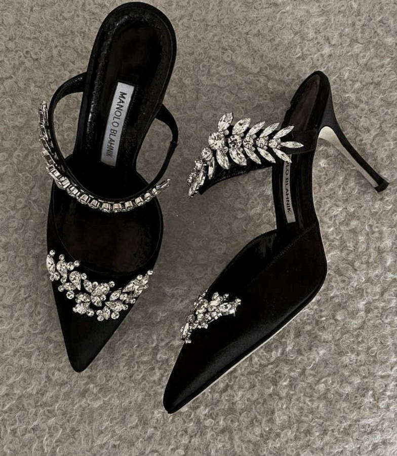 鞋子 桌布 壁紙 — 優雅的黑色天鵝絨 Manolo Blahnik 高跟鞋，飾有閃閃發光的水晶葉片圖案，放置在質感灰色地毯上。