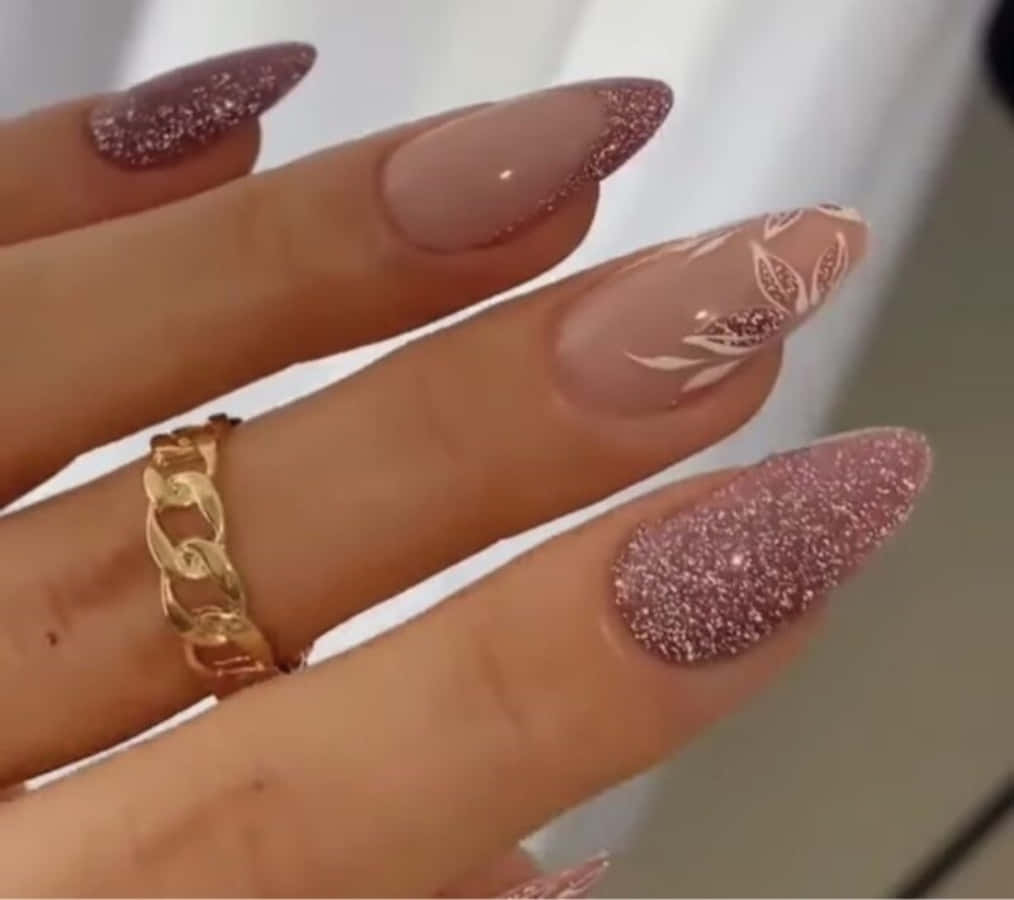 Pink Nail Art 桌布 壁紙 — 優雅美甲的特寫，帶有玫瑰金閃粉和葉子設計，並以金色鏈環戒指點綴。