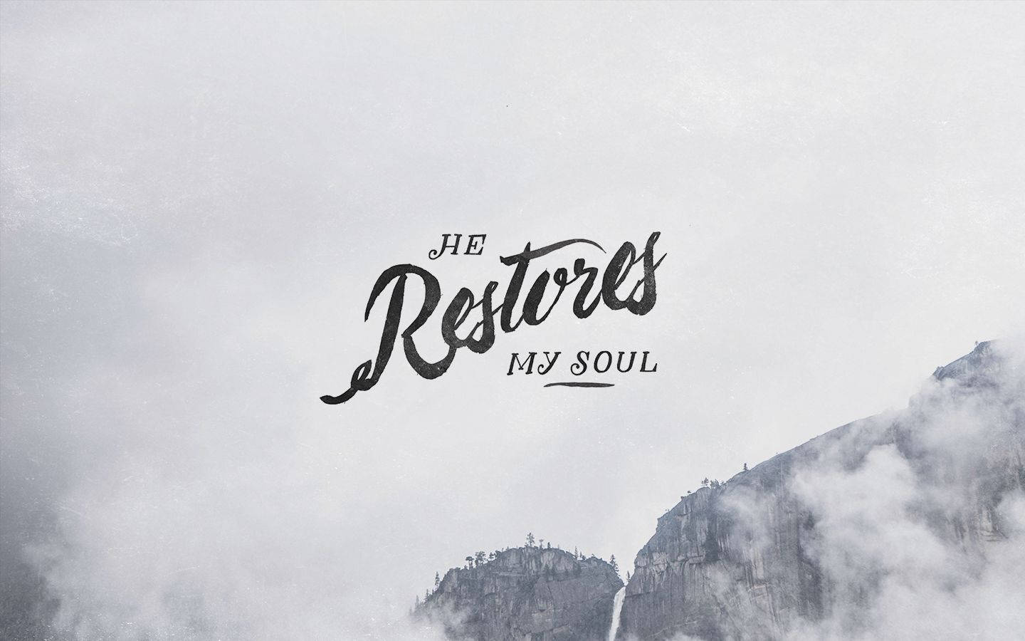 基督教 桌布 壁紙 — 優雅黑色字體寫著「He Restores My Soul」，背景是霧氣繚繞的山巒和柔和灰色雲層。