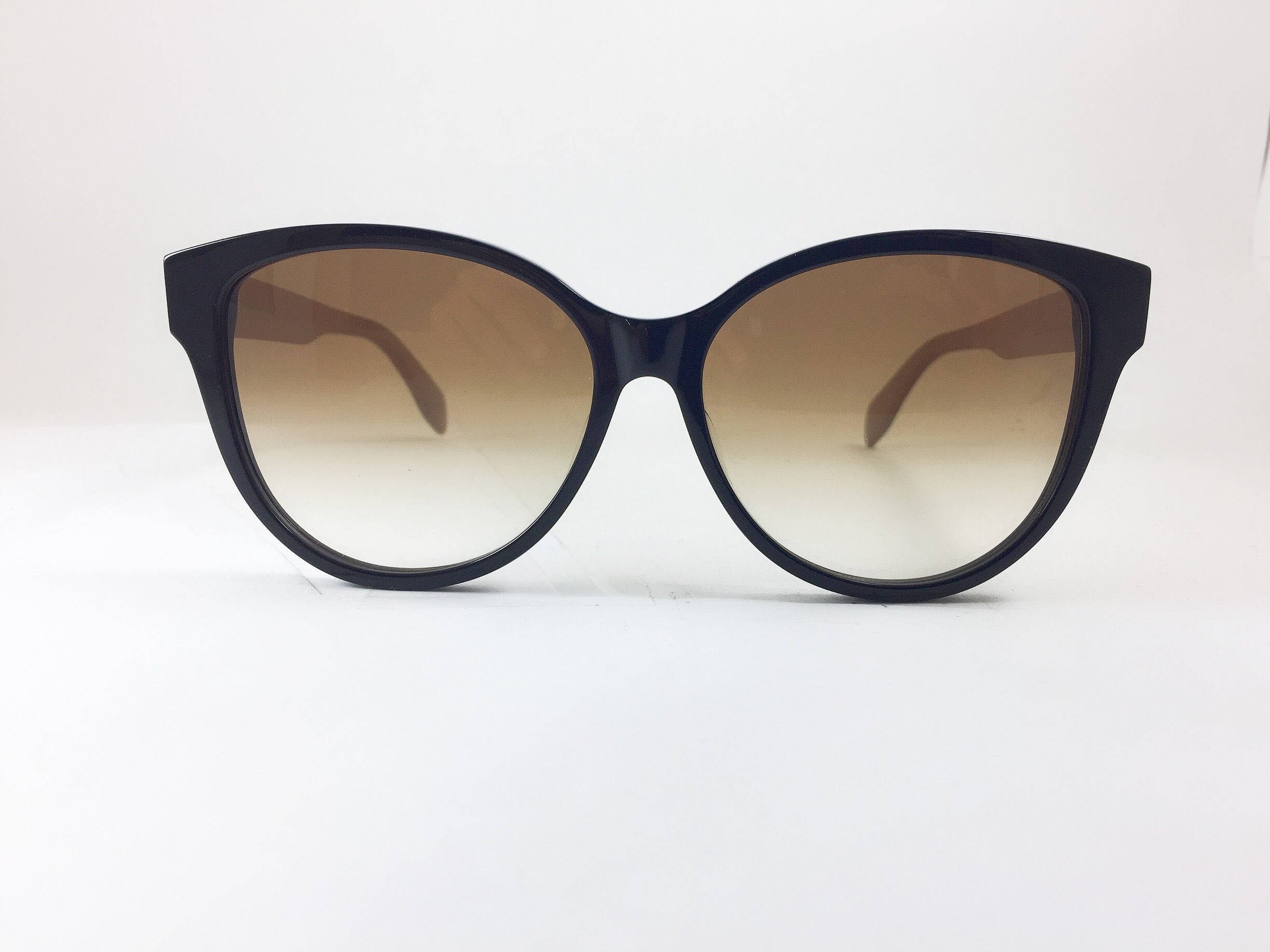 Sunglasses 桌布 壁紙 — 優雅黑色貓眼太陽眼鏡，配漸變棕色鏡片，置於純白表面中央。
