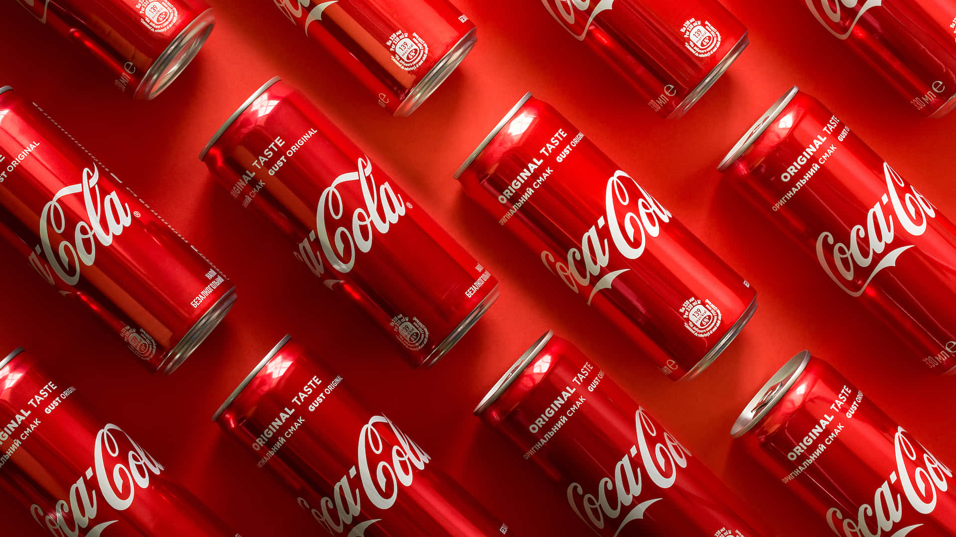 coca cola 桌布 壁紙 — 充滿光澤的可口可樂罐以動態對角線圖案排列的鮮紅色背景。