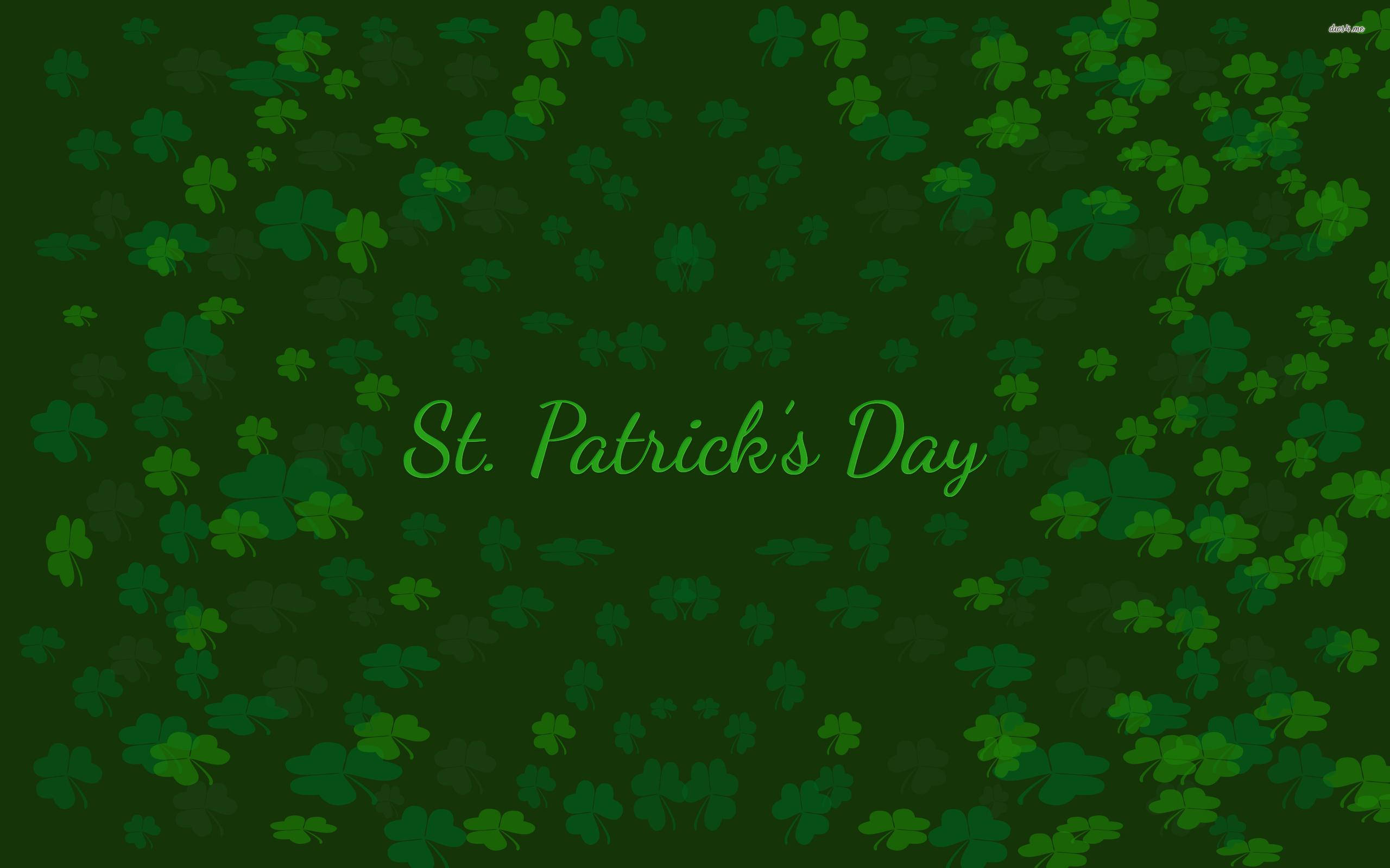 St Patricks Day Birthday 桌布 壁紙 — 充滿散落三葉草和草書聖派翠克節文字的節日綠色背景。