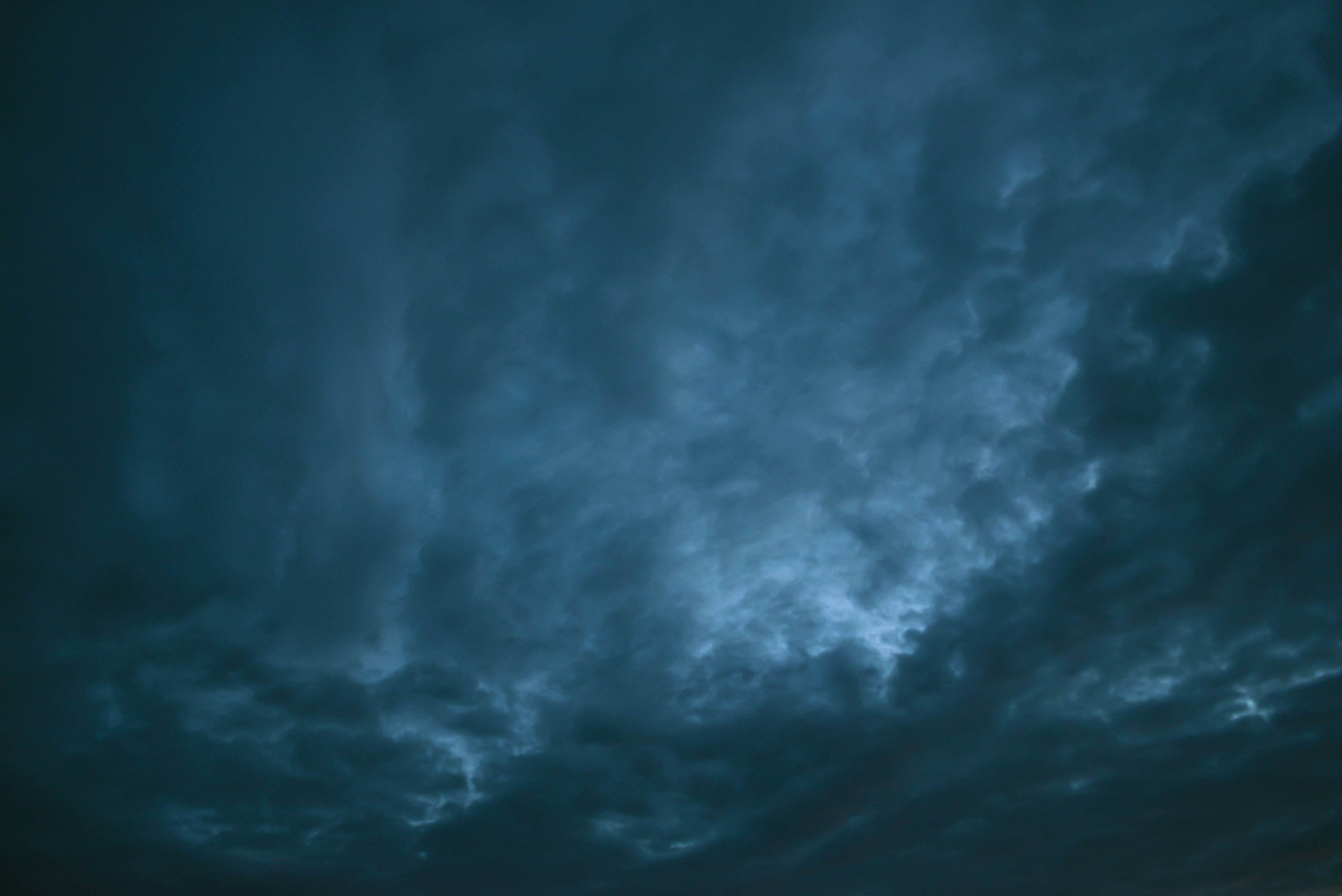 Cloud 桌布 壁紙 — 充滿旋轉深藍色和灰色雲層的戲劇性暴風雨天空，被微弱的閃電照亮。