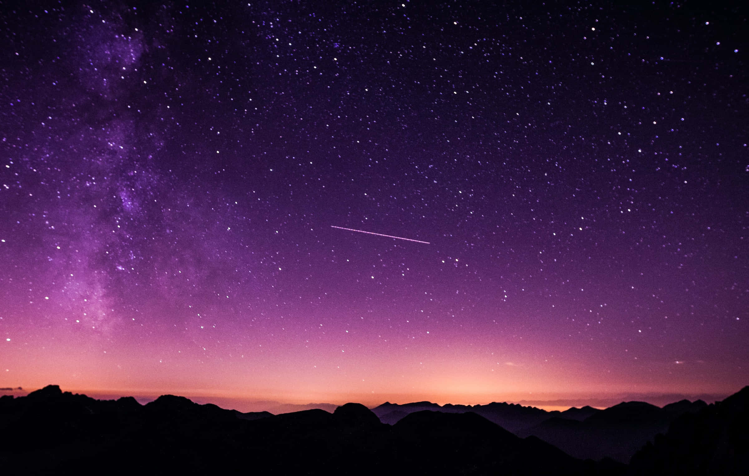 meteor 桌布 壁紙 — 充滿星星和流星的鮮豔紫色和粉紅色夜空，在黑暗山脈剪影上方拱起。
