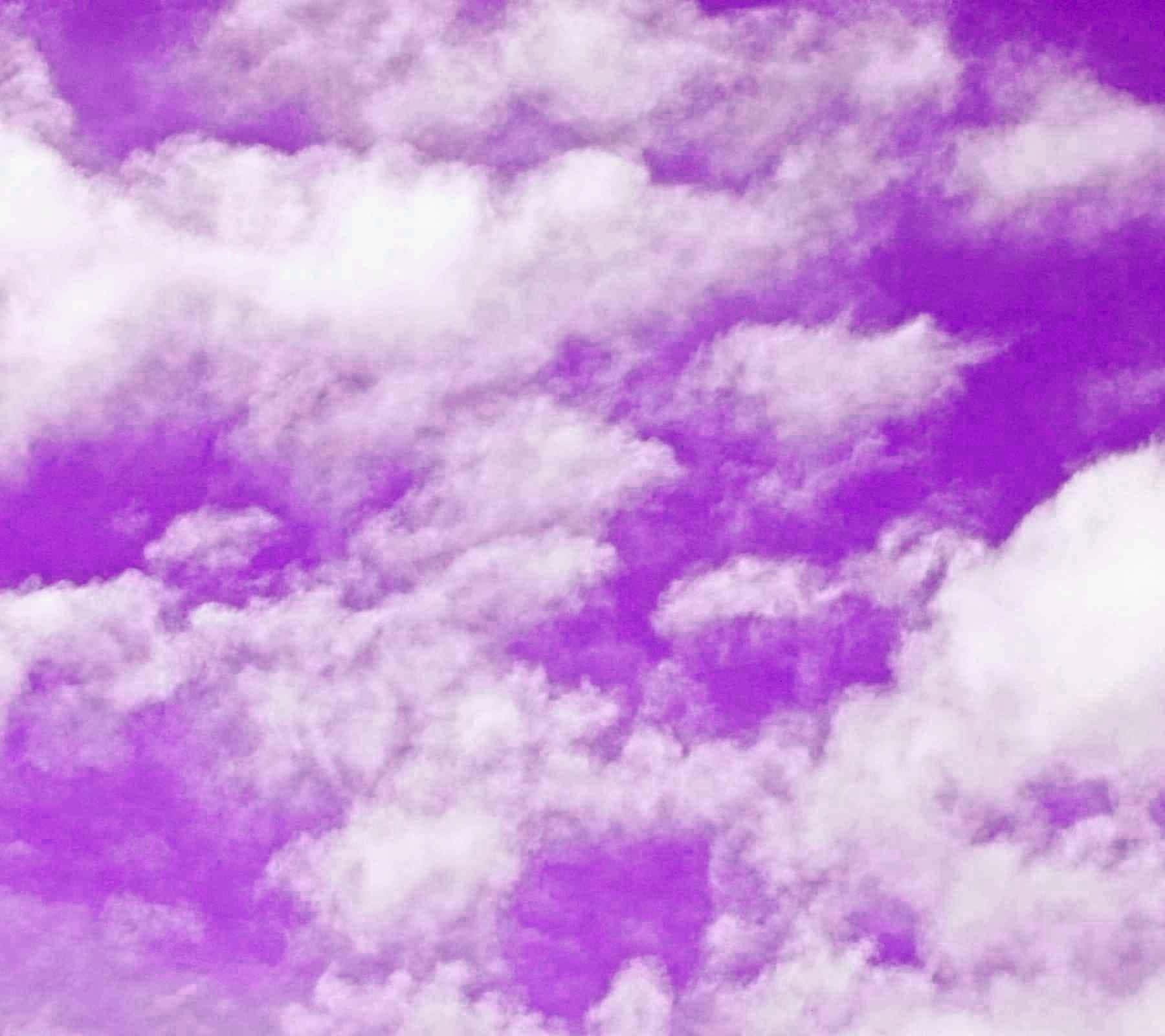 Purple Clouds 桌布 壁紙 — 充滿柔和白色雲朵的鮮豔紫色天空，營造夢幻氛圍的場景。