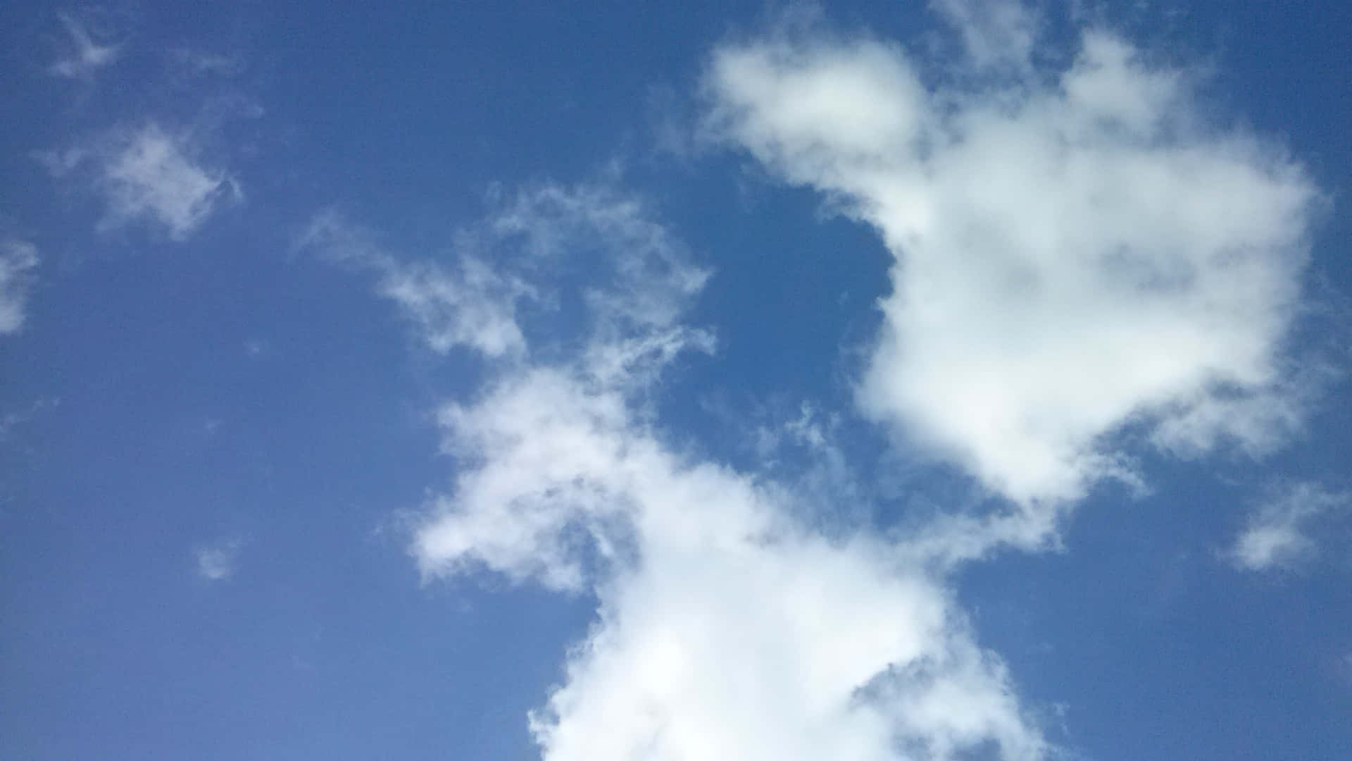 SKY-22 壁紙 — 充滿柔和白色雲朵的鮮豔藍天，雲朵在地平線上飄移。