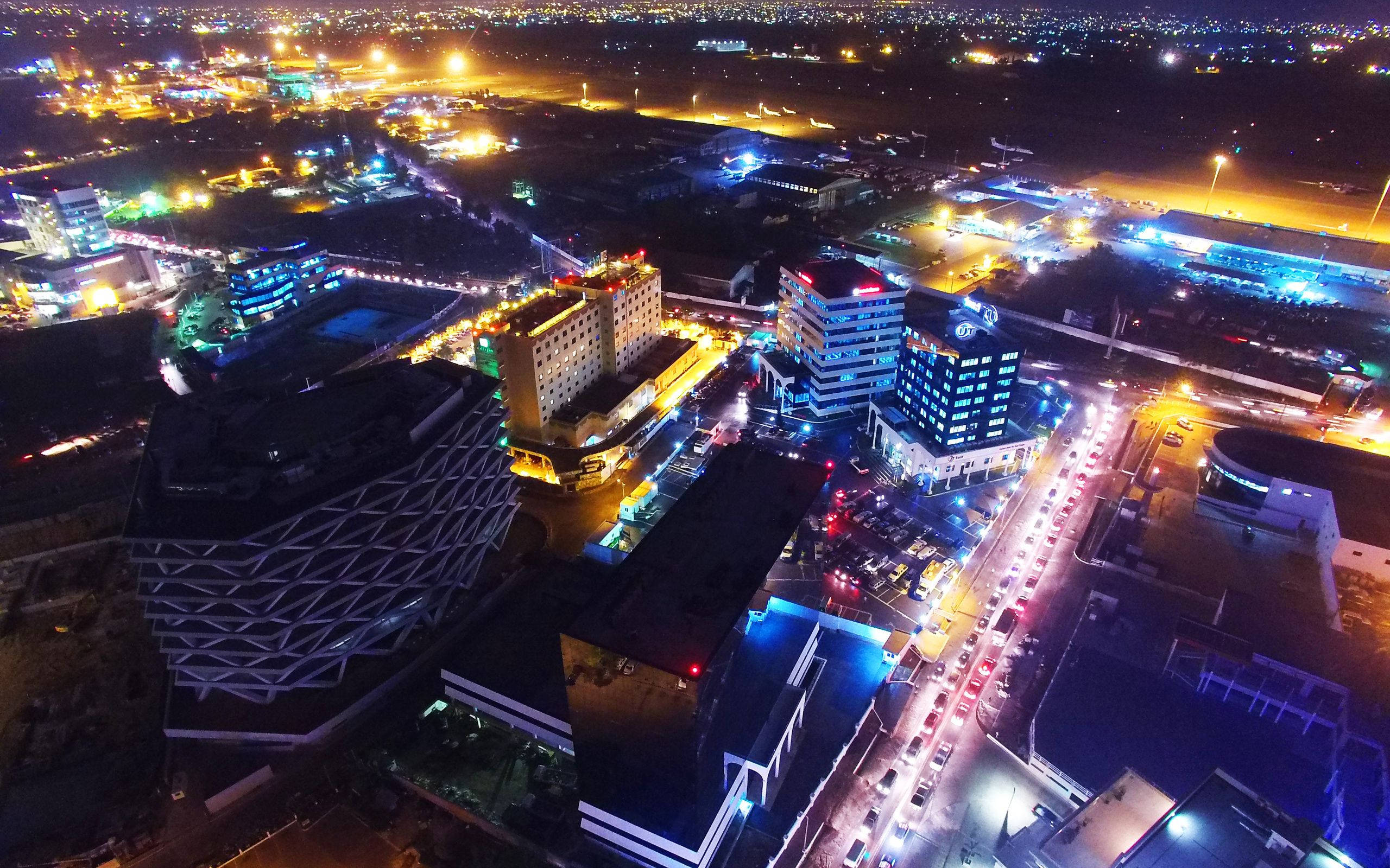 迦納 桌布 壁紙 — 充滿活力城市景觀的空中夜景，建築物閃閃發光，繁忙街道上佈滿車燈。