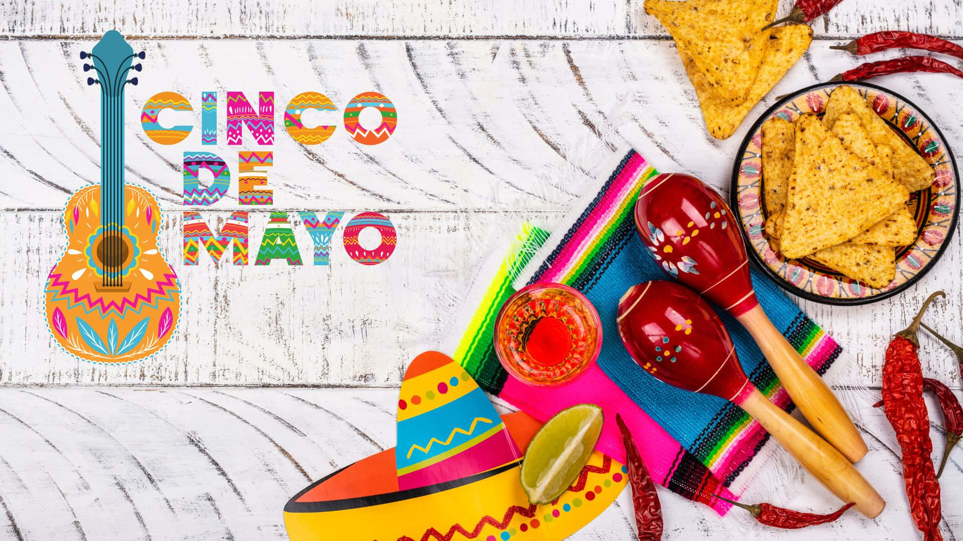 Cinco De Mayo 桌布 壁紙 — 充滿活力的 Cinco de Mayo 慶祝物品，如吉他、沙鈴、闊邊帽和薯片，排列在質樸的白色木質表面上。
