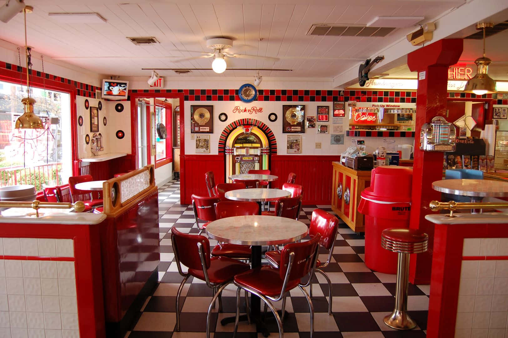 jukebox 桌布 壁紙 — 充滿活力的1950年代餐廳，配有紅色乙烯基卡座、棋盤格地板和復古點唱機，在溫暖燈光下閃耀。