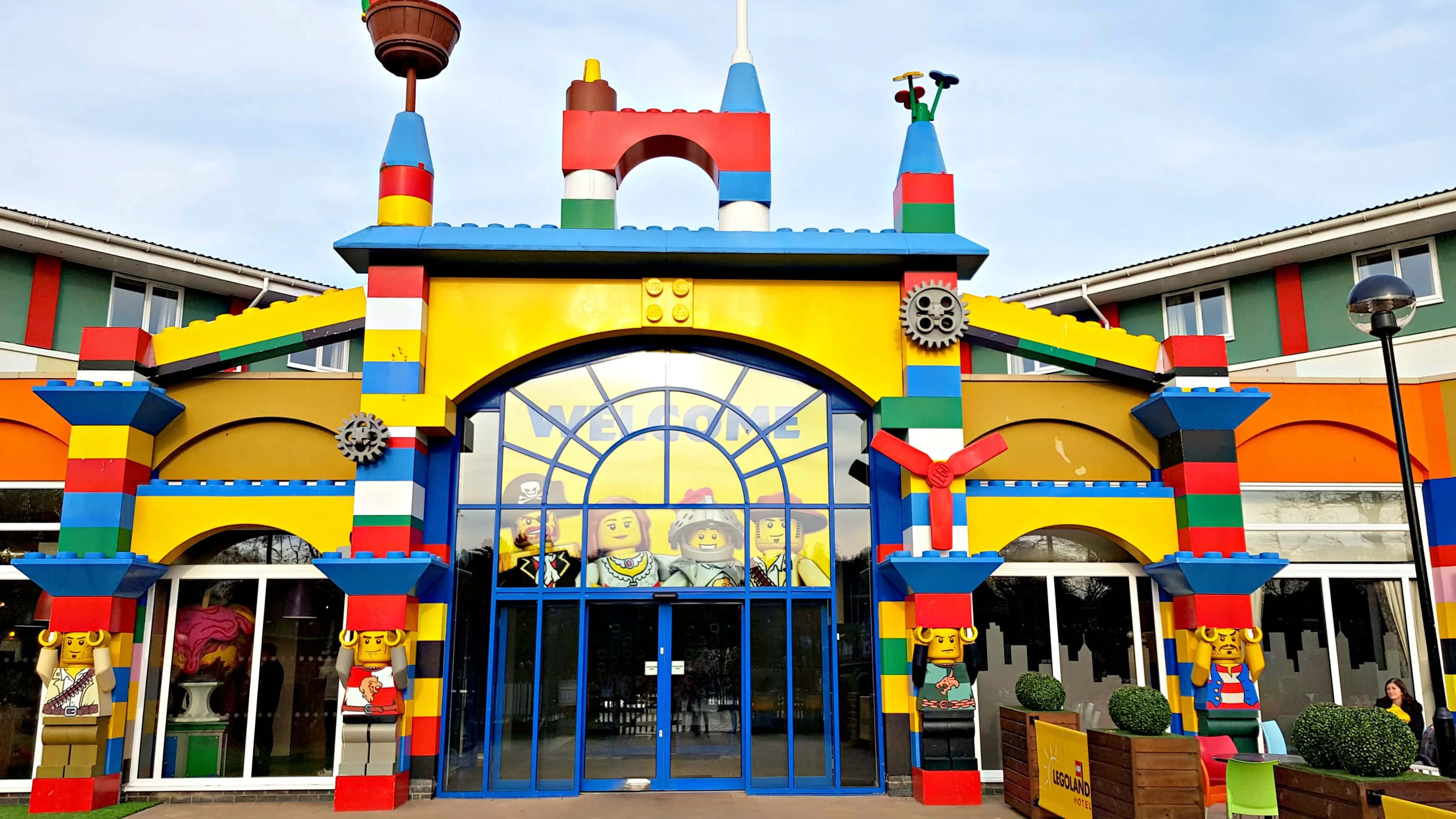 Legoland 桌布 壁紙 — 充滿活力的LEGO主題入口，色彩繽紛的積木塔和迷你人偶雕像在晴朗的天空下。