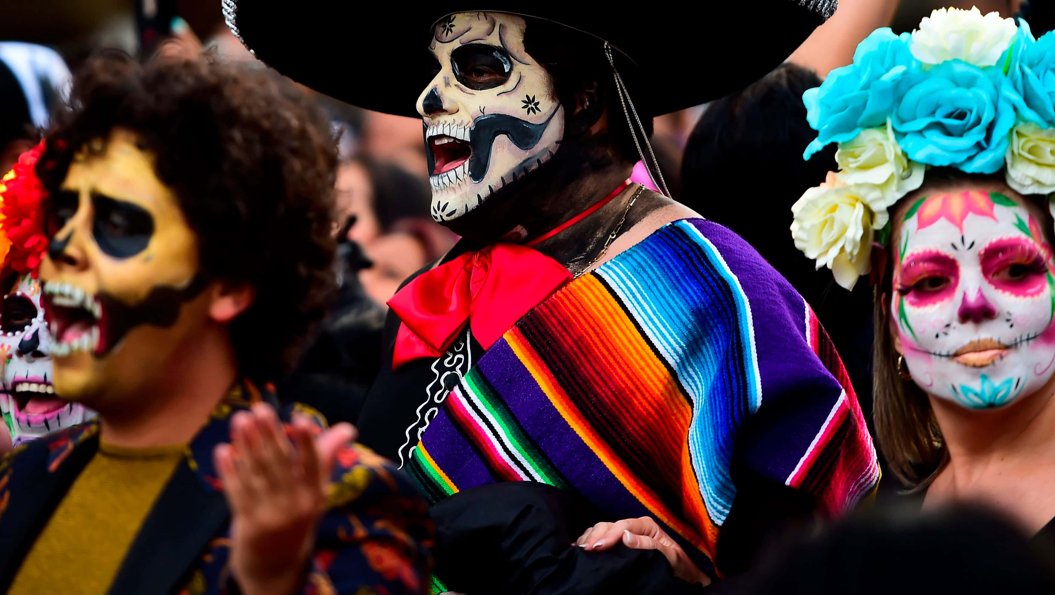 Mexican 桌布 壁紙 — 充滿活力的亡靈節慶祝活動，人們裝飾著色彩繽紛的糖骷髏妝容和傳統墨西哥服飾。