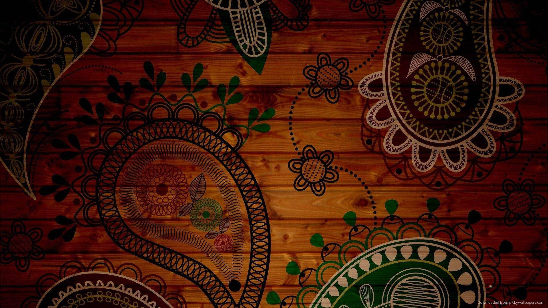 Paisley 桌布 壁紙 — 充滿活力的佩斯利和花卉圖案，以綠色和金色點綴在溫暖琥珀色調的豐富紋理木質表面上。