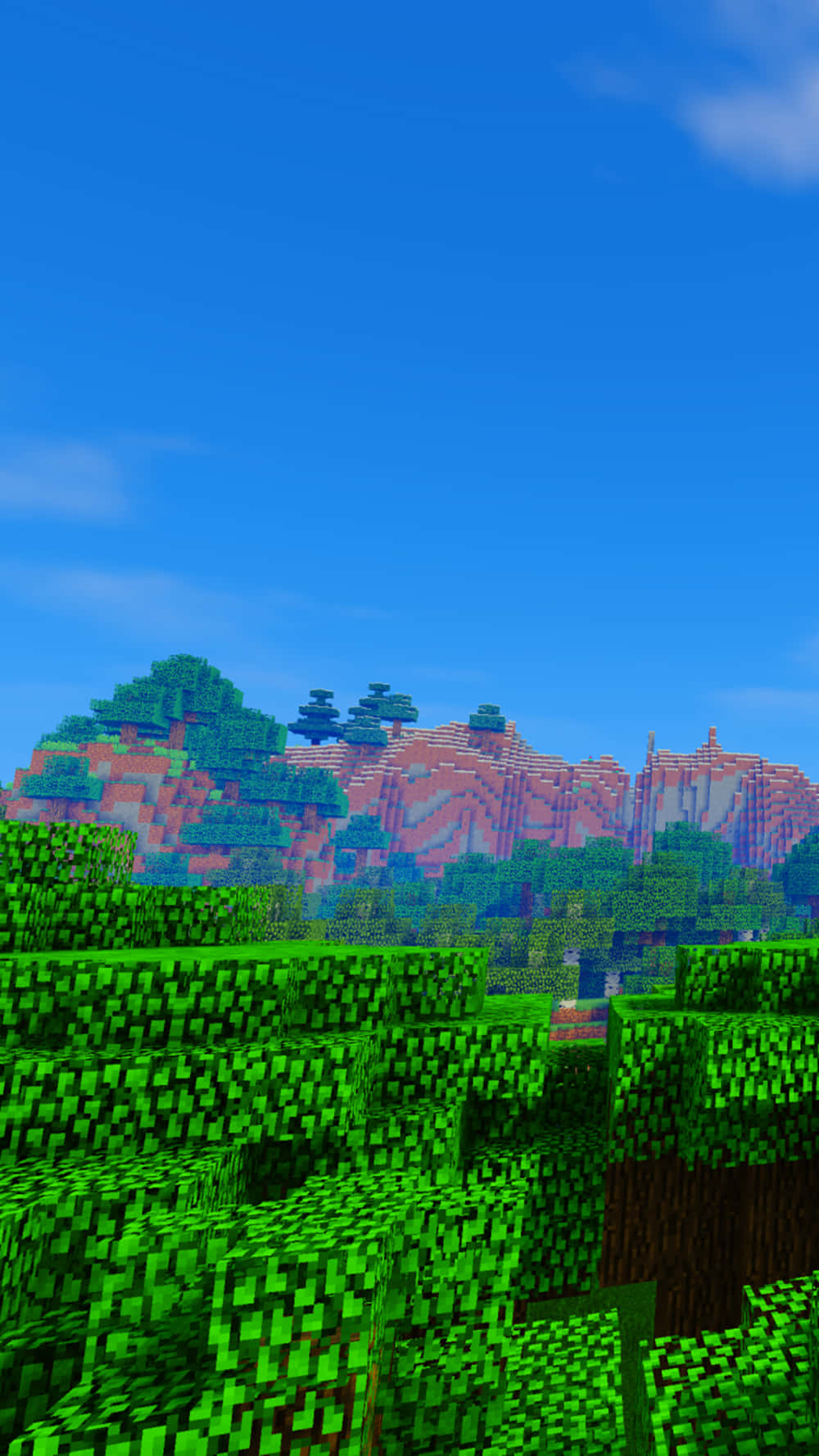 風景 桌布 壁紙 — 充滿活力的像素化Minecraft景觀，茂密的綠色樹木和紅色條紋山脈在晴朗的藍天下。