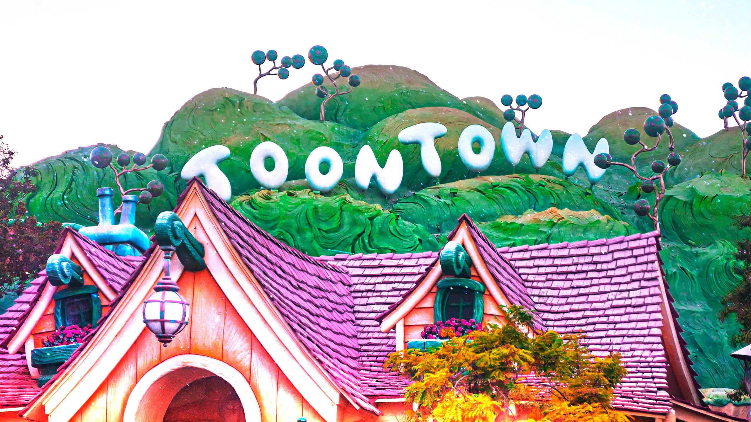 在綠色山丘上的Toontown標誌下，色彩繽紛的卡通房屋帶有紫色屋頂。