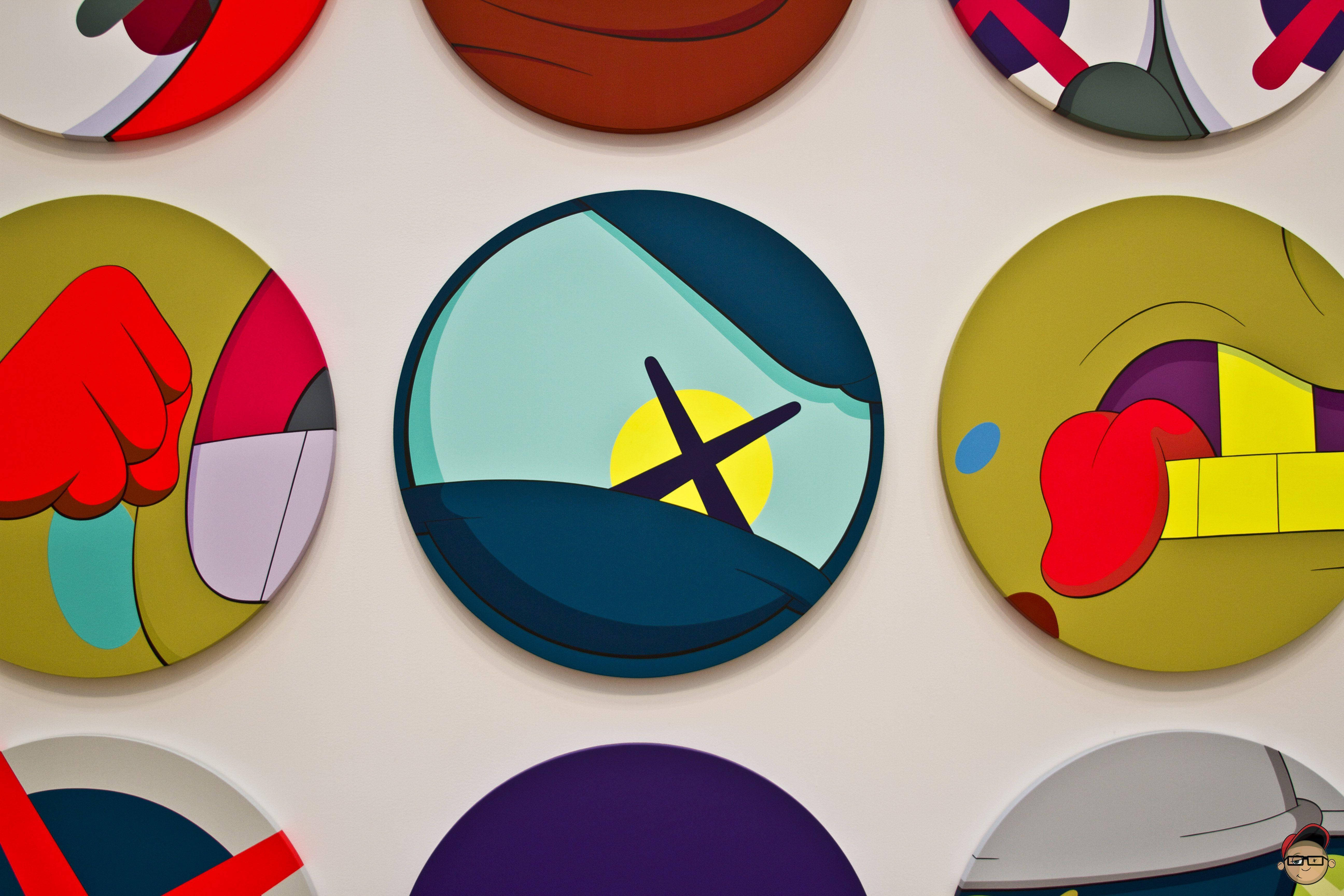 KAWS 桌布 壁紙 — 充滿活力的圓形抽象藝術品，色彩大膽，幾何形狀，安裝在白色牆壁上。