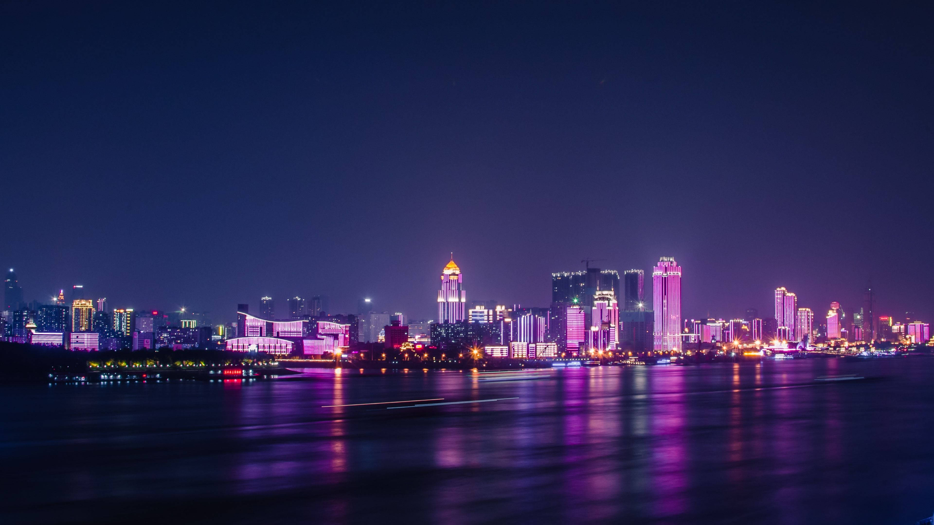 Wuhan 桌布 壁紙 — 充滿活力的城市夜景，紫色和粉紅色的霓虹燈倒映在平靜的河面上。