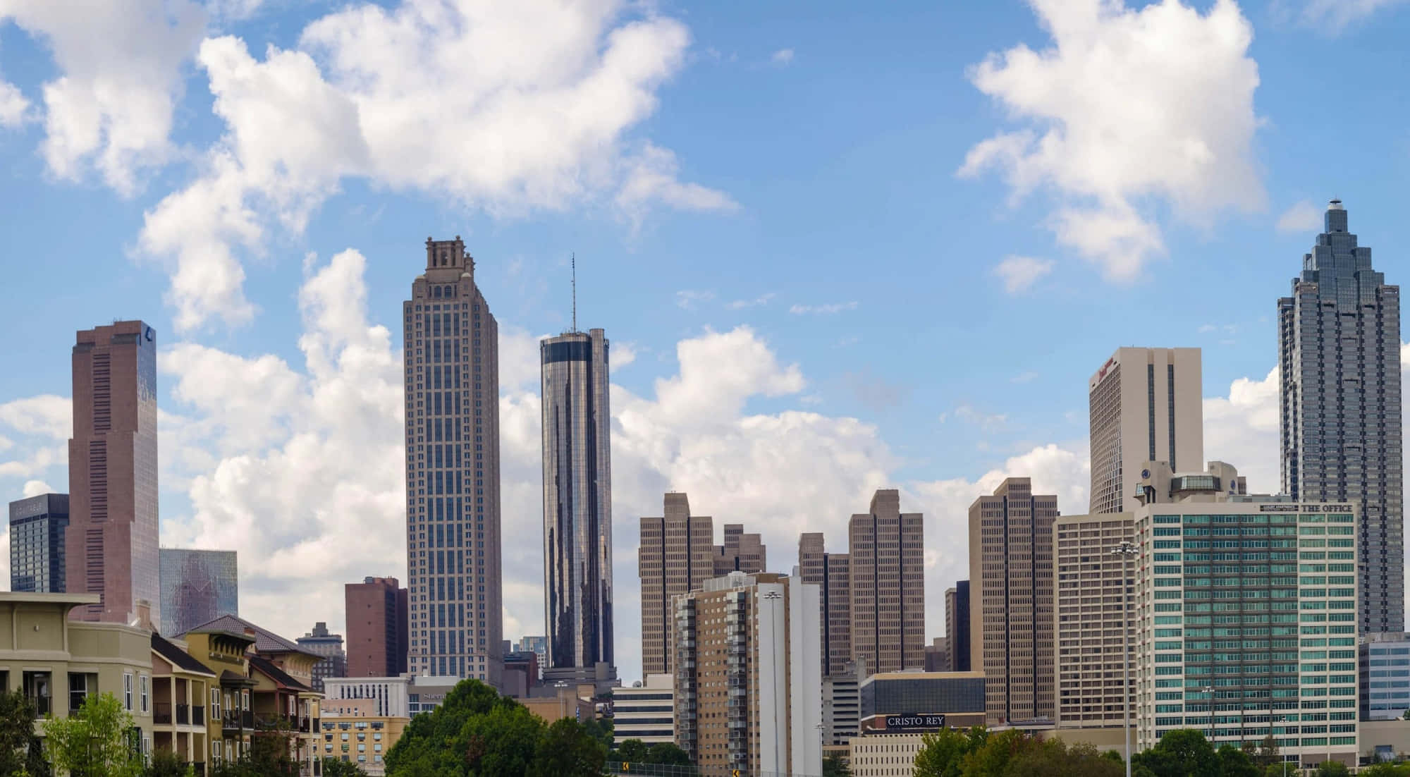 Atlanta Georgia 桌布 壁紙 — 充滿活力的城市天際線，高聳的摩天大樓在明亮的藍天下點綴著蓬鬆的白雲。