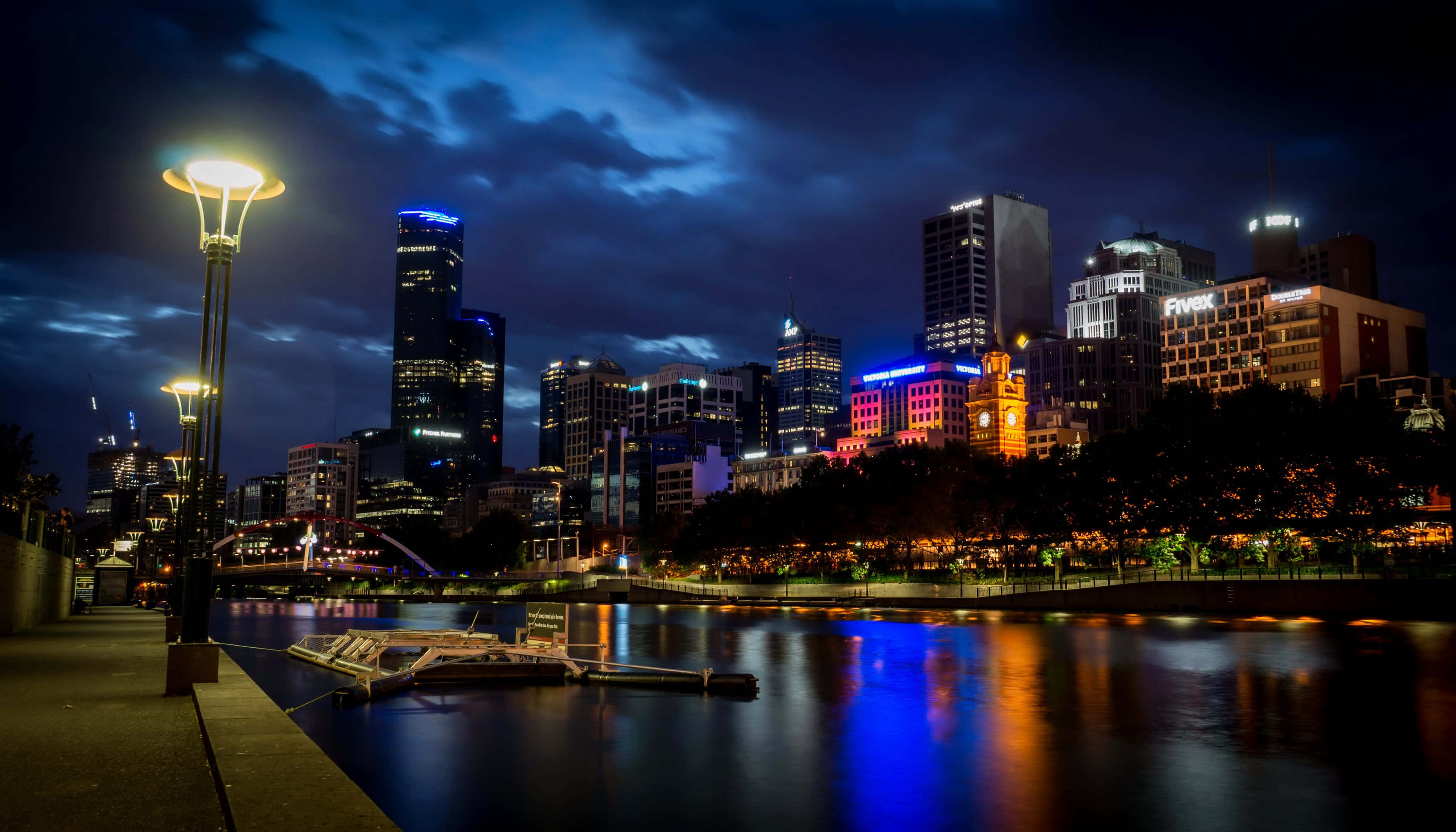 Adelaide 桌布 壁紙 — 充滿活力的城市天際線在夜晚倒映在平靜的水面上，襯托著憂鬱的藍天和發光的路燈。