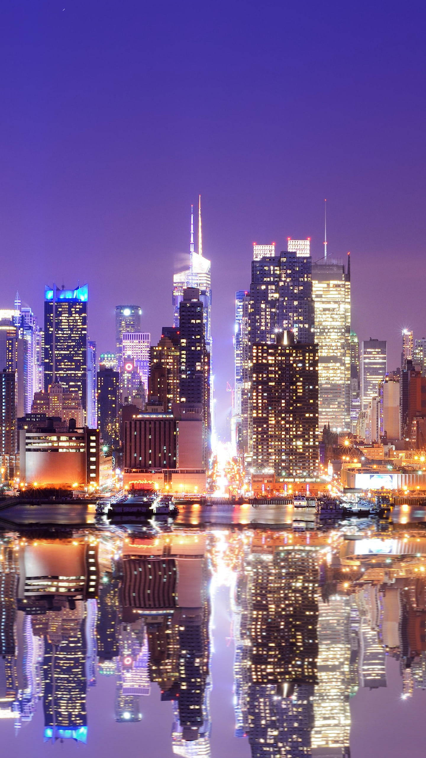 New 桌布 壁紙 — 充滿活力的城市天際線夜景，摩天大樓在紫色天空下閃耀，倒映在平靜的水面上。