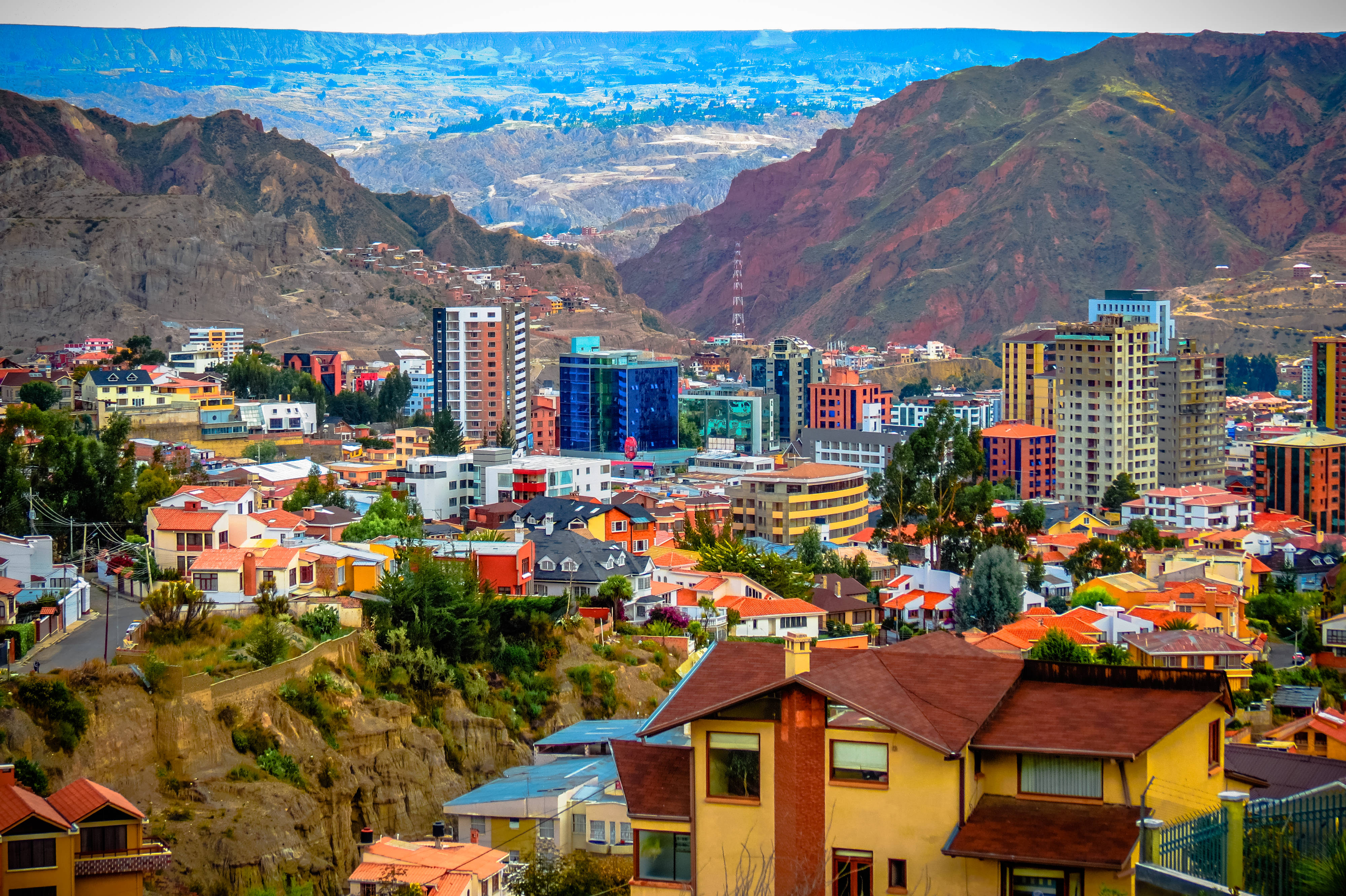 Bolivia 桌布 壁紙 — 充滿活力的城市景觀，坐落在崎嶇的山脈中，色彩繽紛的建築物和遙遠的山谷，在清澈的藍天下。