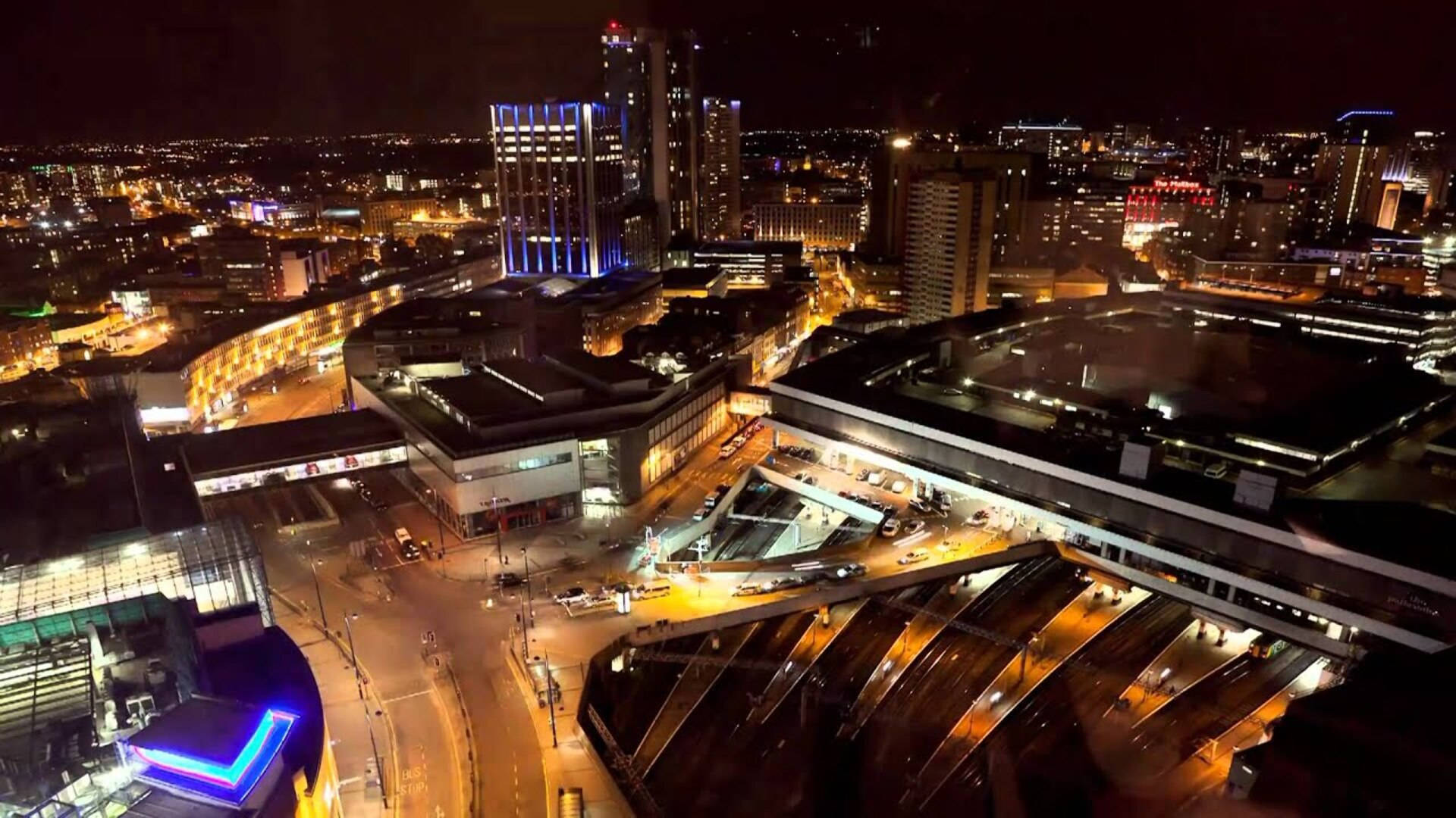 Birmingham 桌布 壁紙 — 充滿活力的城市景觀夜間鳥瞰圖，下方有發光的摩天大樓和明亮的街道。