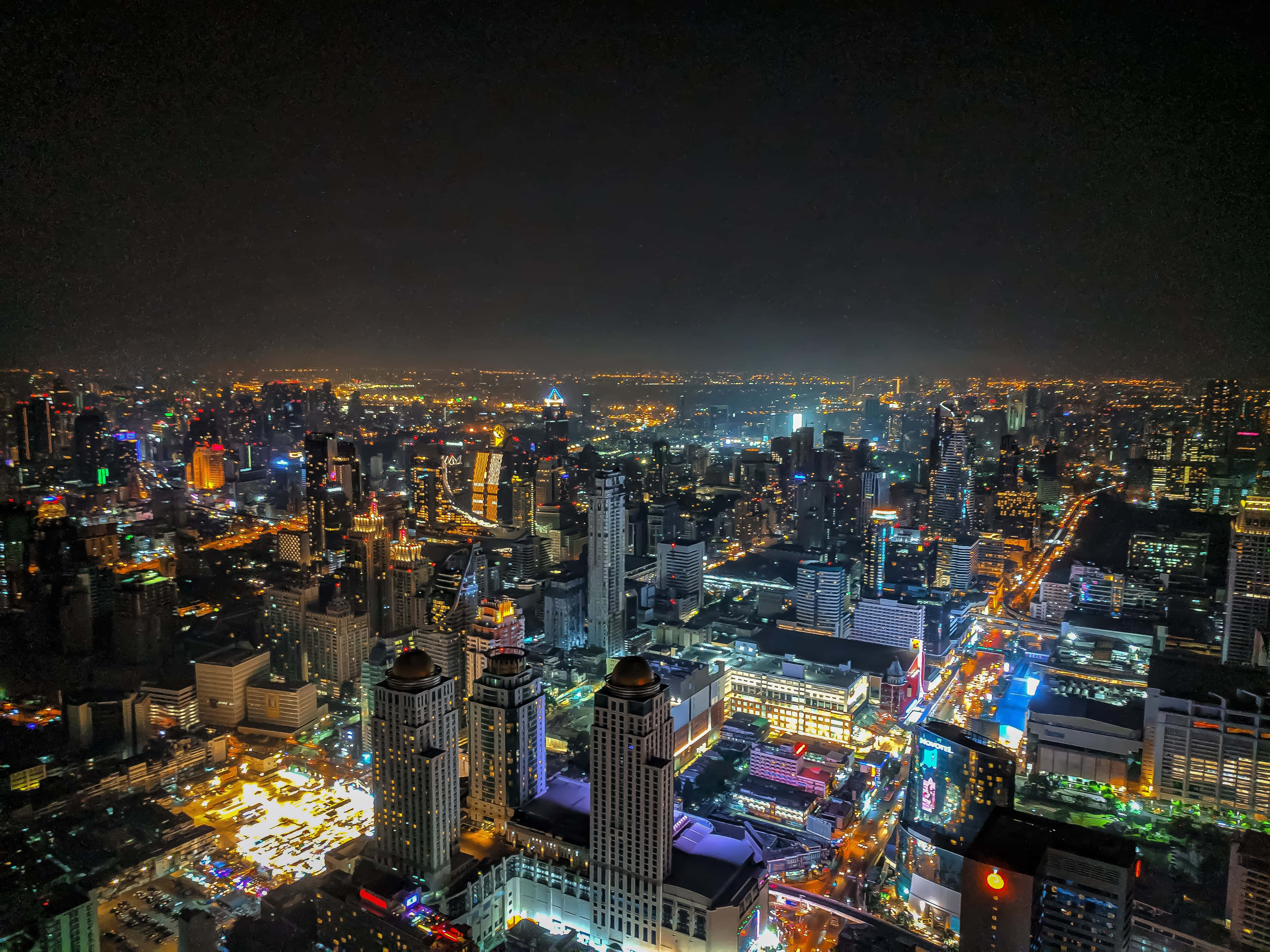 Twitter Header 桌布 壁紙 — 充滿活力的城市景觀的夜間鳥瞰圖，閃爍的摩天大樓和燈火通明的街道延伸至地平線。