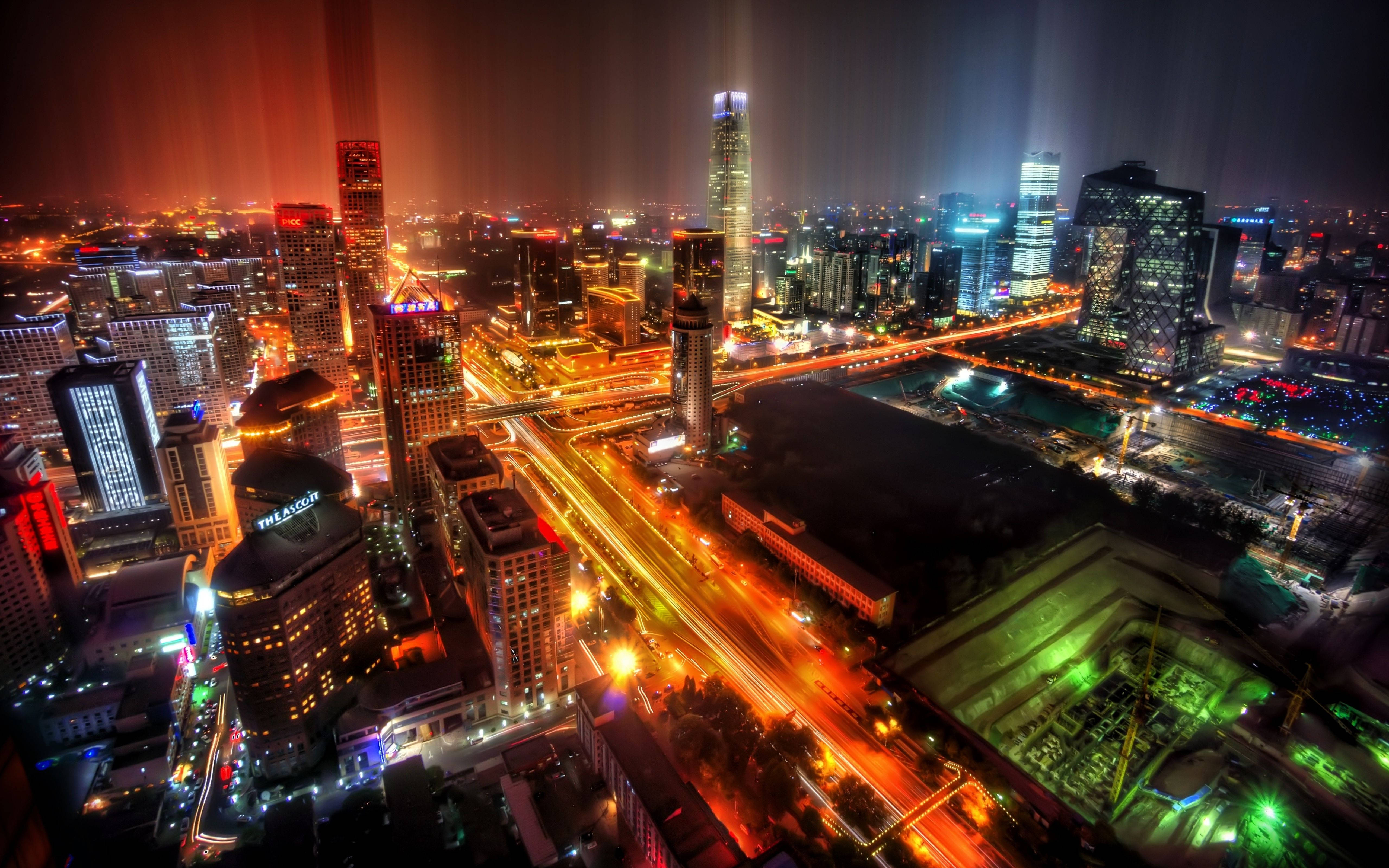 城市 桌布 壁紙 — 充滿活力的城市景觀的空中夜景，發光的摩天大樓和流動的交通燈照亮了城市範圍。
