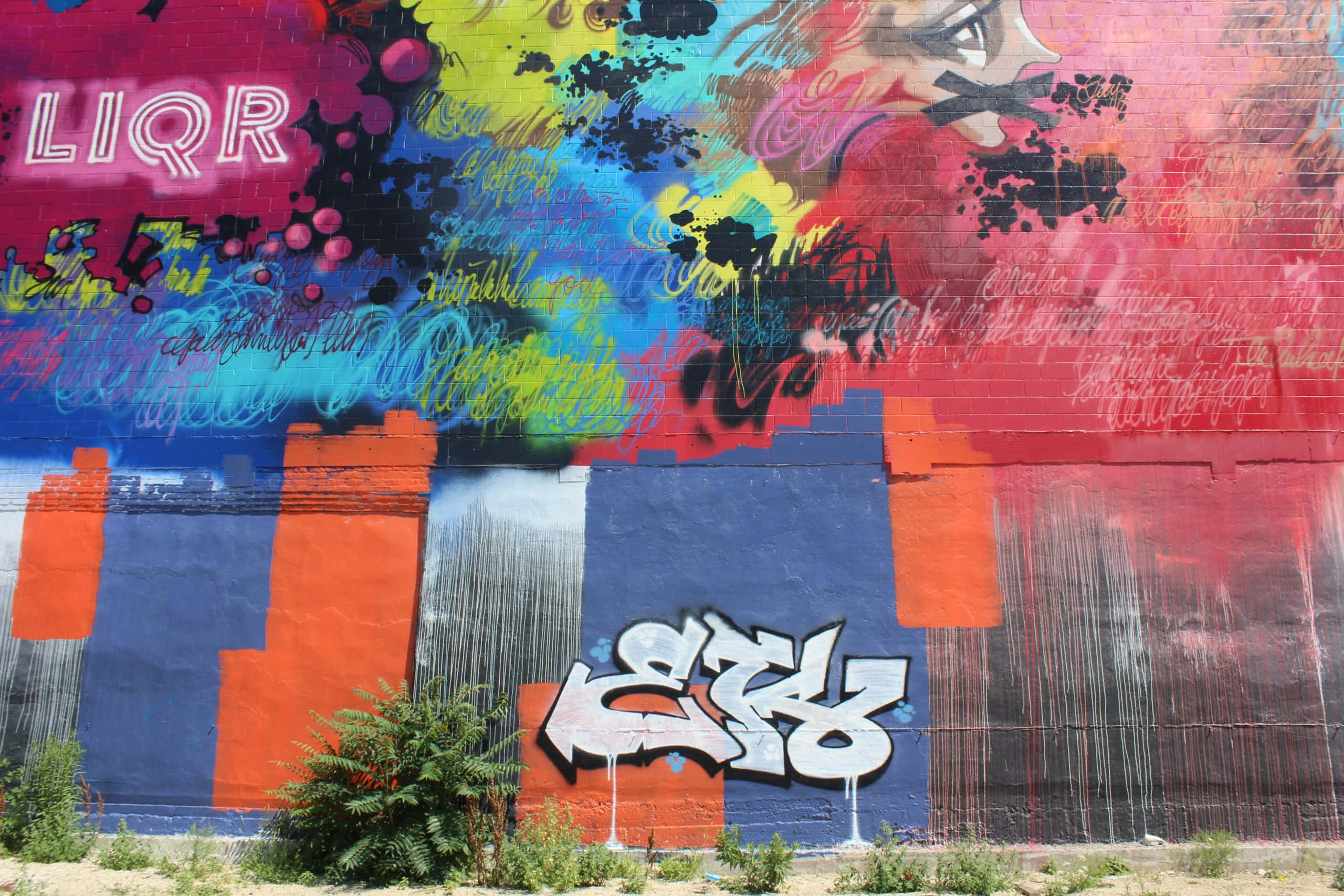 Graffiti Art 桌布 壁紙 — 充滿活力的塗鴉壁畫，以鮮豔色彩和風格化文字覆蓋磚牆，在明亮的日光下。