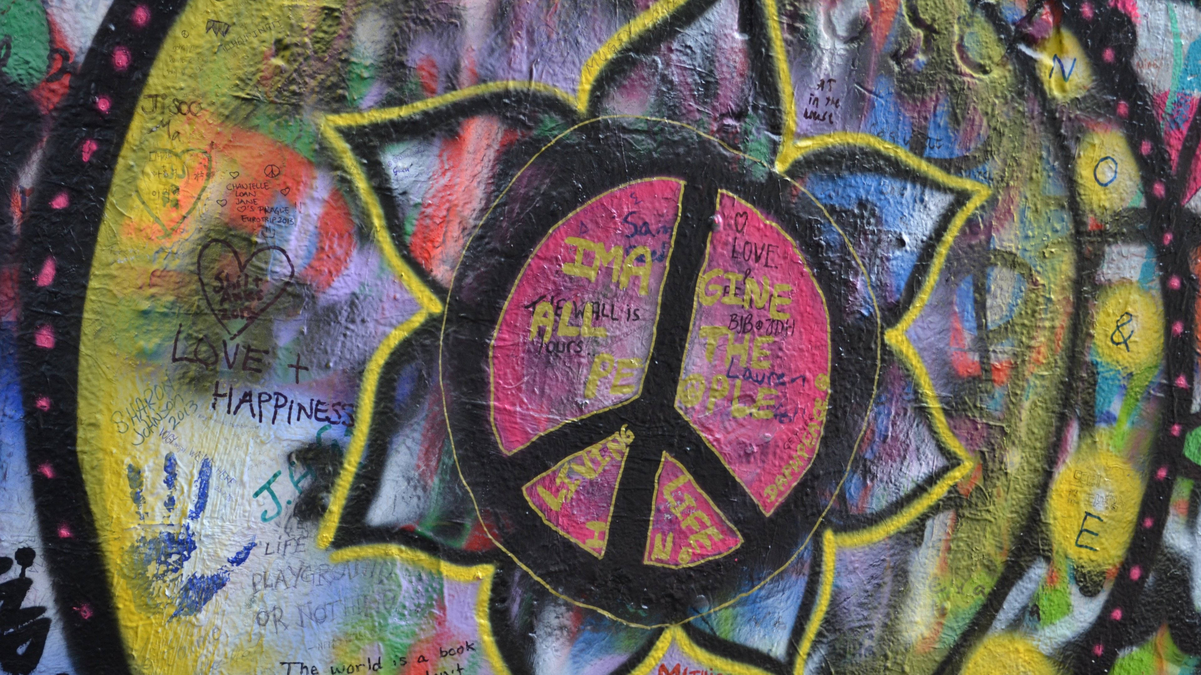 Peace 桌布 壁紙 — 充滿活力的塗鴉壁畫，在紋理牆上有一個大膽的粉紅色和平標誌、手寫訊息和彩色手印。