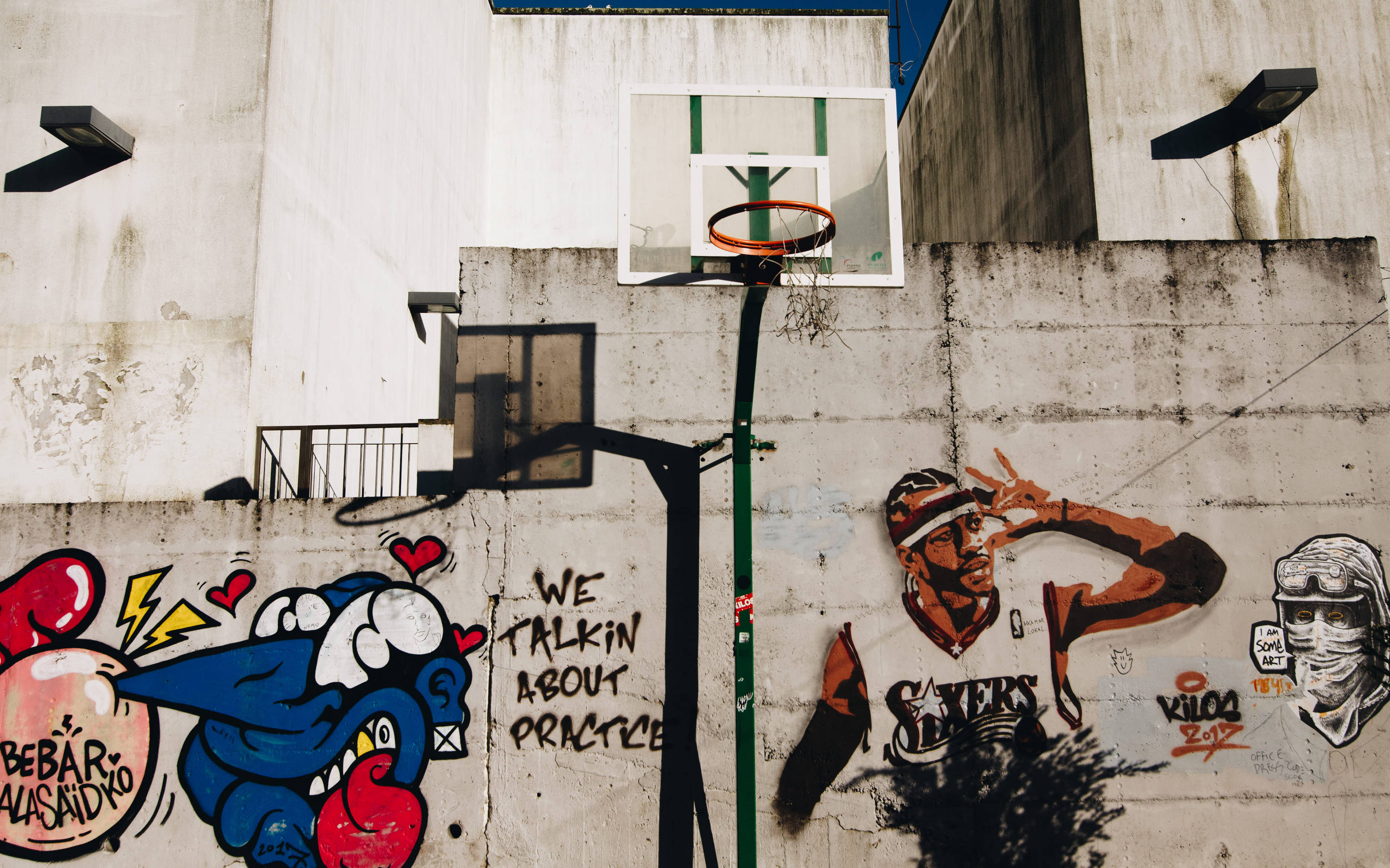 NBA 桌布 壁紙 — 充滿活力的塗鴉藝術覆蓋了城市小巷中圍繞籃球框的混凝土牆。