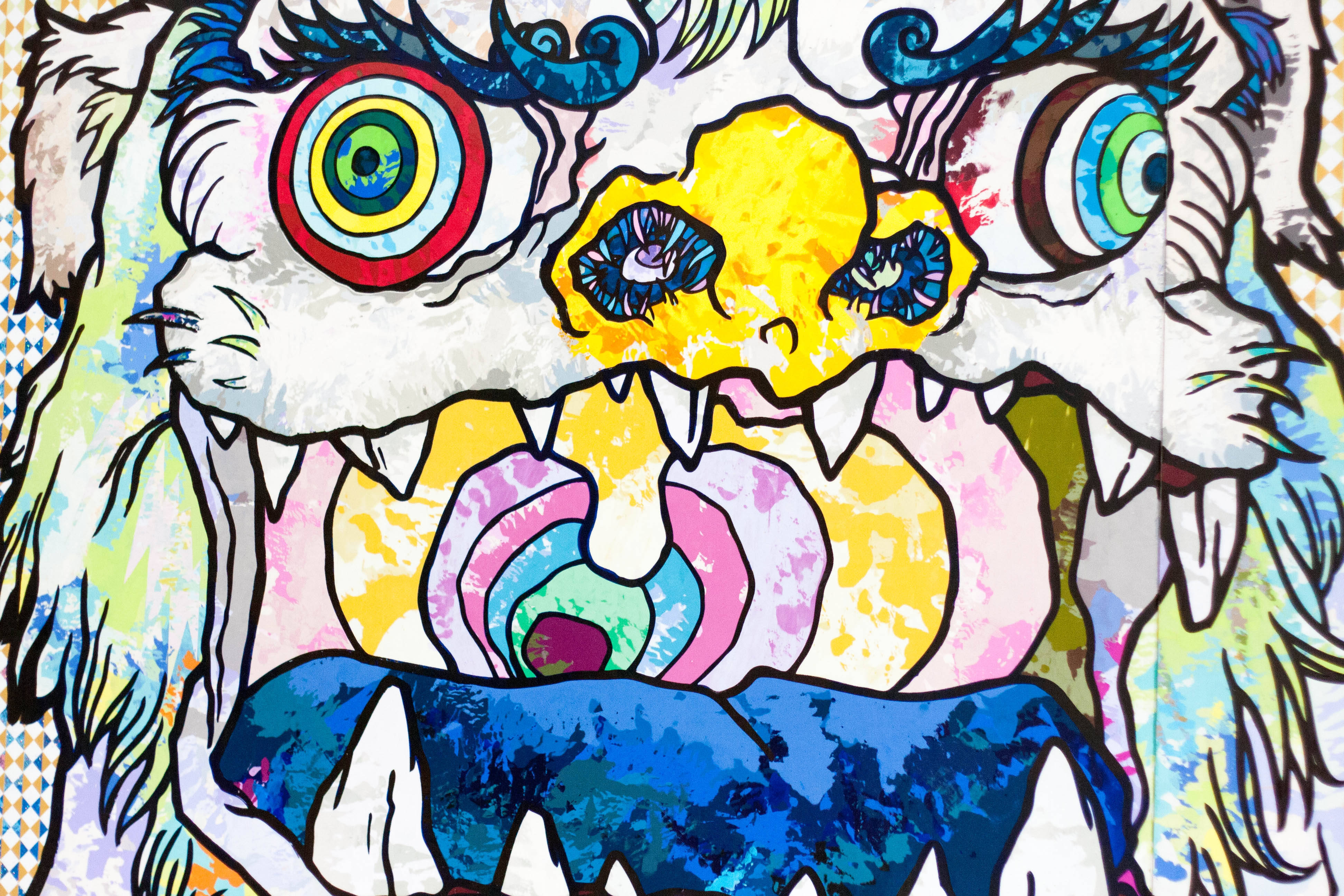 4K 桌布 壁紙 — 充滿活力的塗鴉風格壁畫，描繪了一隻風格化的野獸，擁有迷幻的眼睛和鋒利的牙齒，背景為圖案。