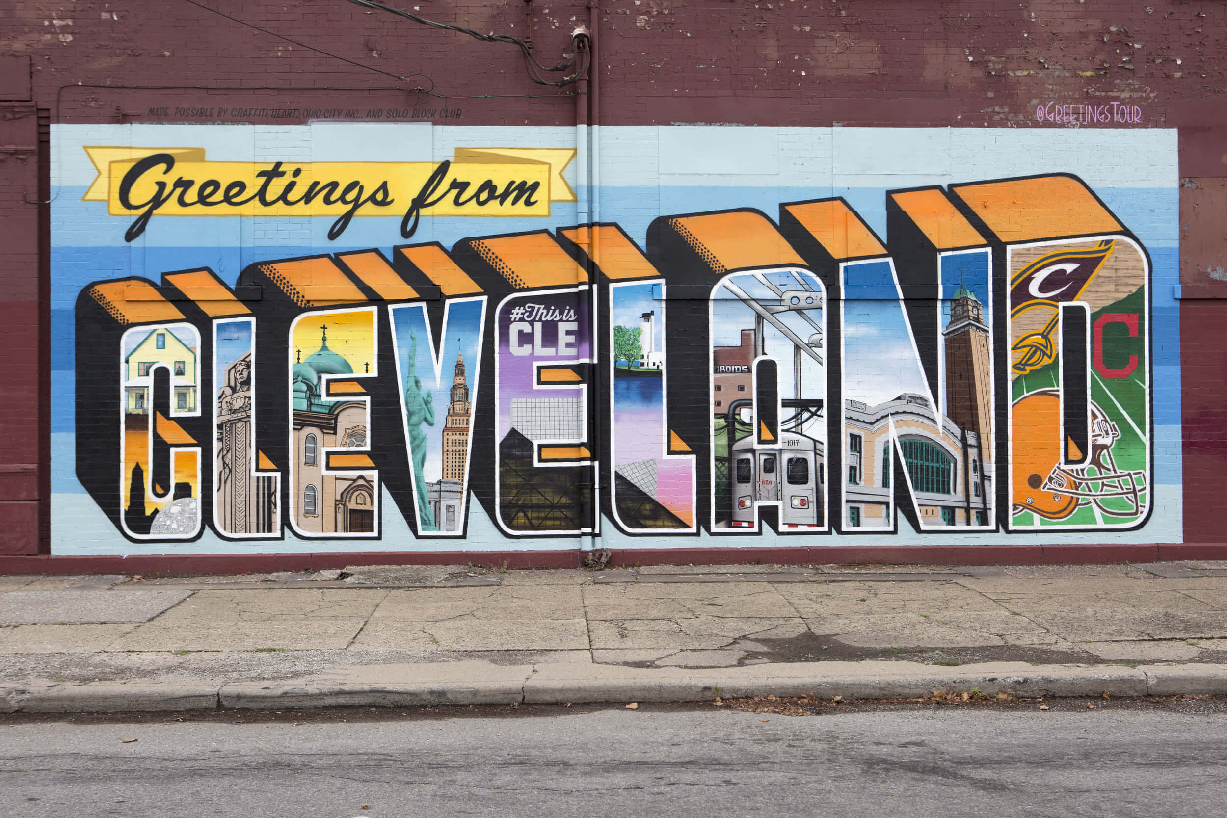 Graffiti Art 桌布 壁紙 — 充滿活力的壁畫，在磚牆上拼出 'CLEVELAND'，每個字母內包含標誌性的當地地標和體育圖像。