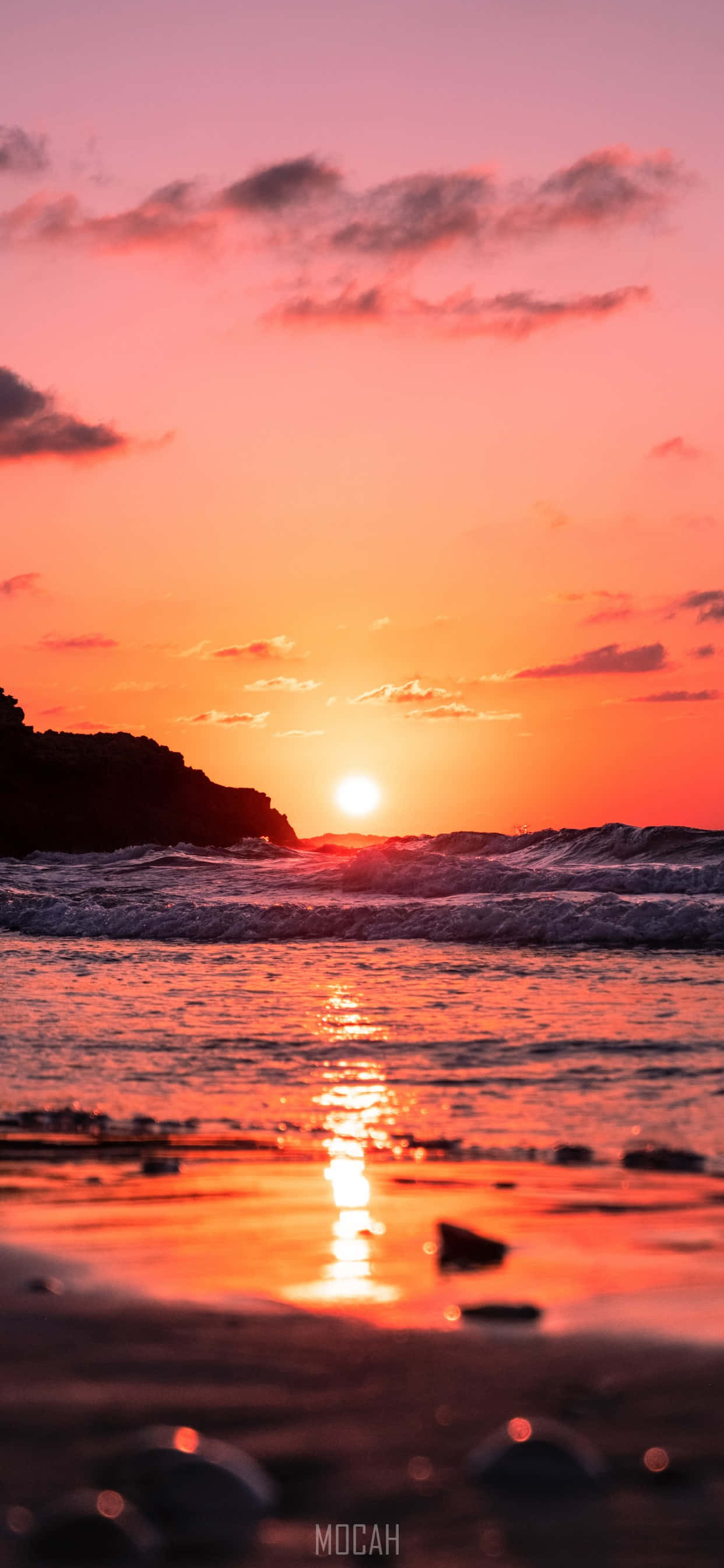 Sunrise iPhone 桌布 壁紙 — 充滿活力的夕陽將天空和海洋染成火熱的橙色和粉紅色，海浪拍打著岩石海岸。