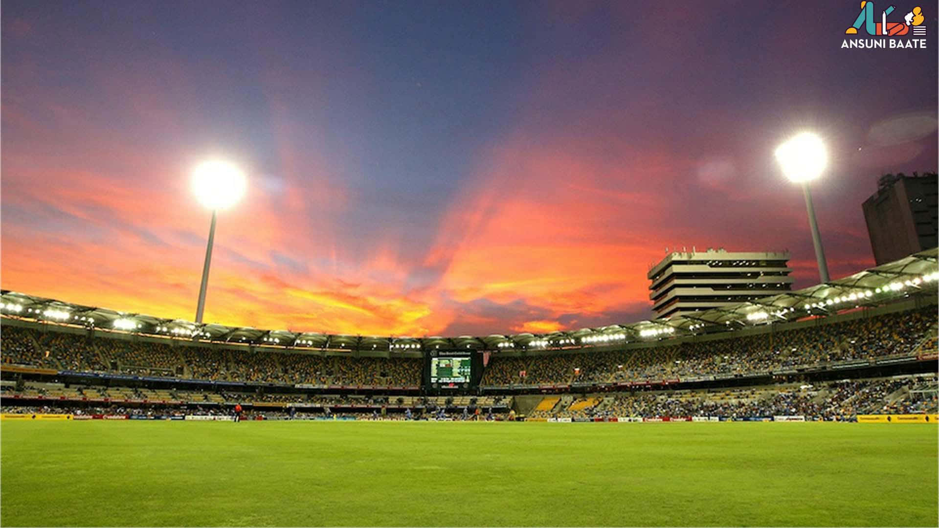 Cricket Ground 桌布 壁紙 — 充滿活力的夕陽將擠滿觀眾的板球場沐浴在火熱的橙色和紫色色調中，泛光燈照亮了綠色的場地。