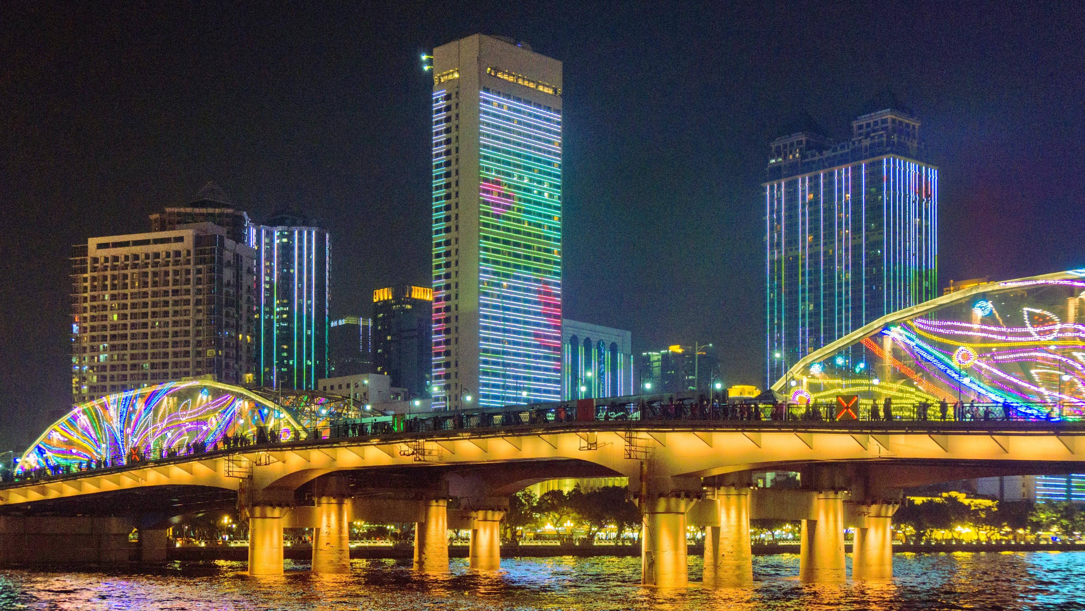 Guangzhou 桌布 壁紙 — 充滿活力的夜景，以一座燈火通明的拱橋橫跨水面，背景是色彩繽紛的摩天大樓。