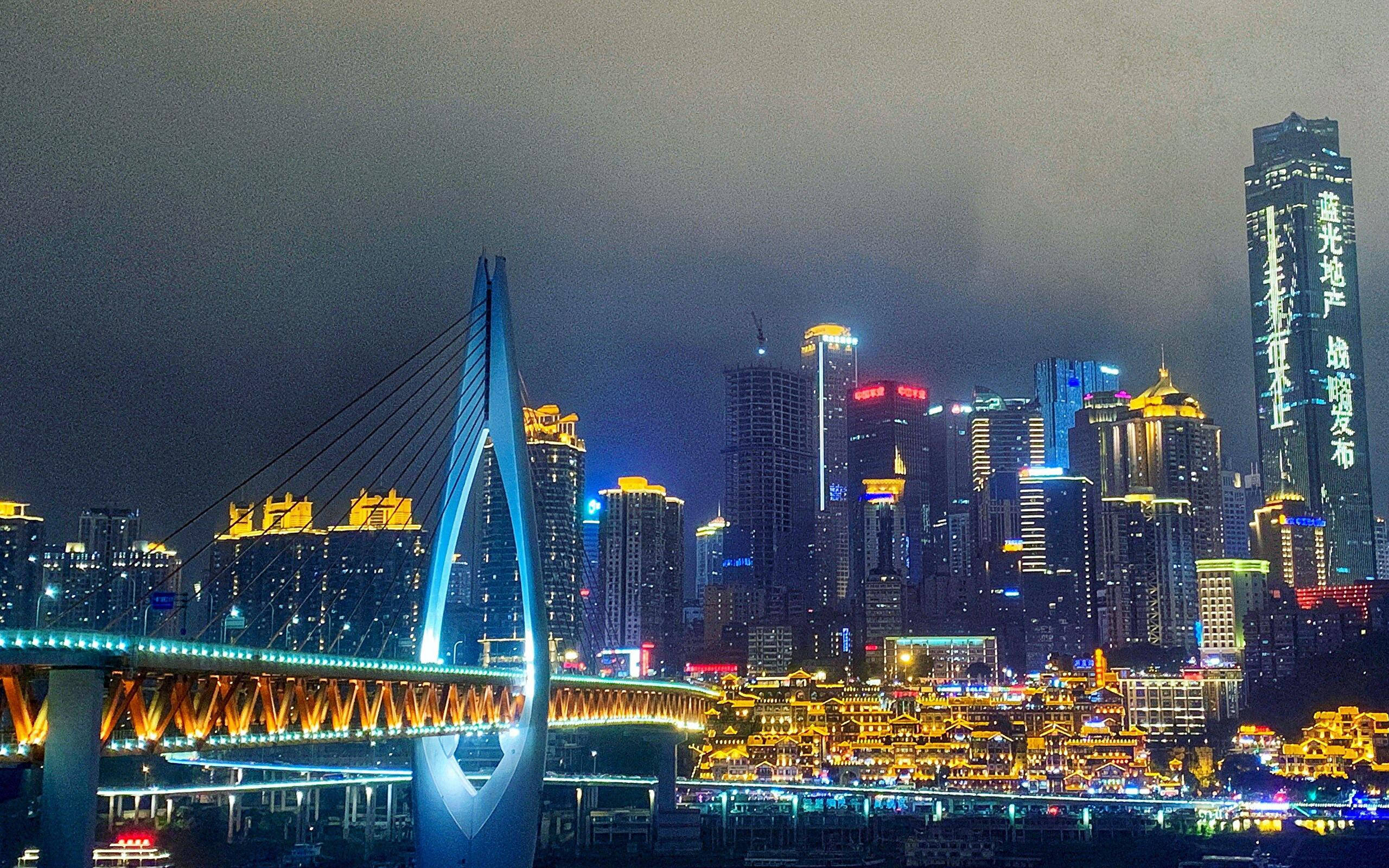 Harbin 桌布 壁紙 — 充滿活力的夜景，有一座發光的現代橋樑和燈火通明的摩天大樓倒映在水面上。