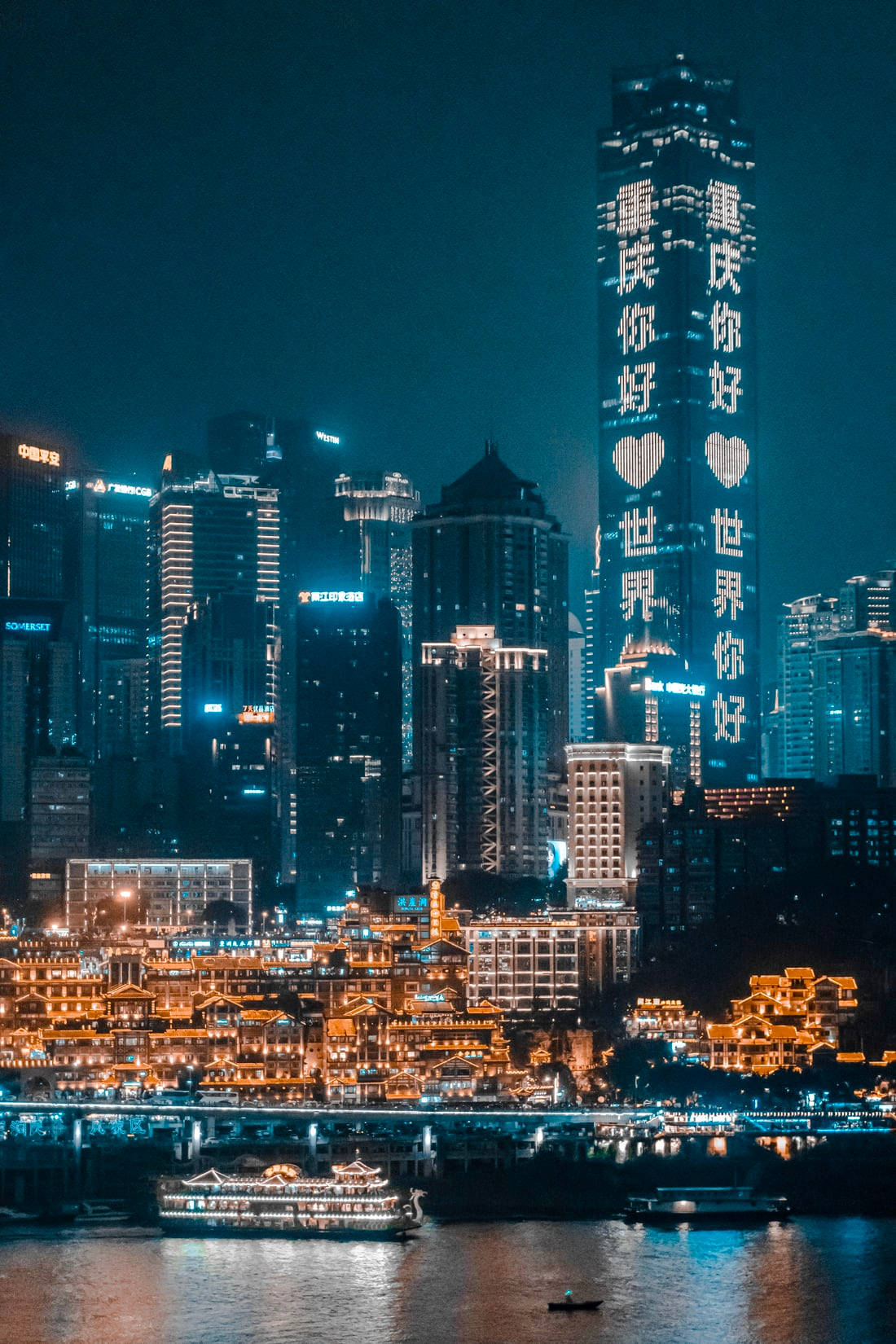 唐人街 桌布 壁紙 — 充滿活力的夜景，河邊有燈火通明的摩天大樓和傳統建築，還有船隻。
