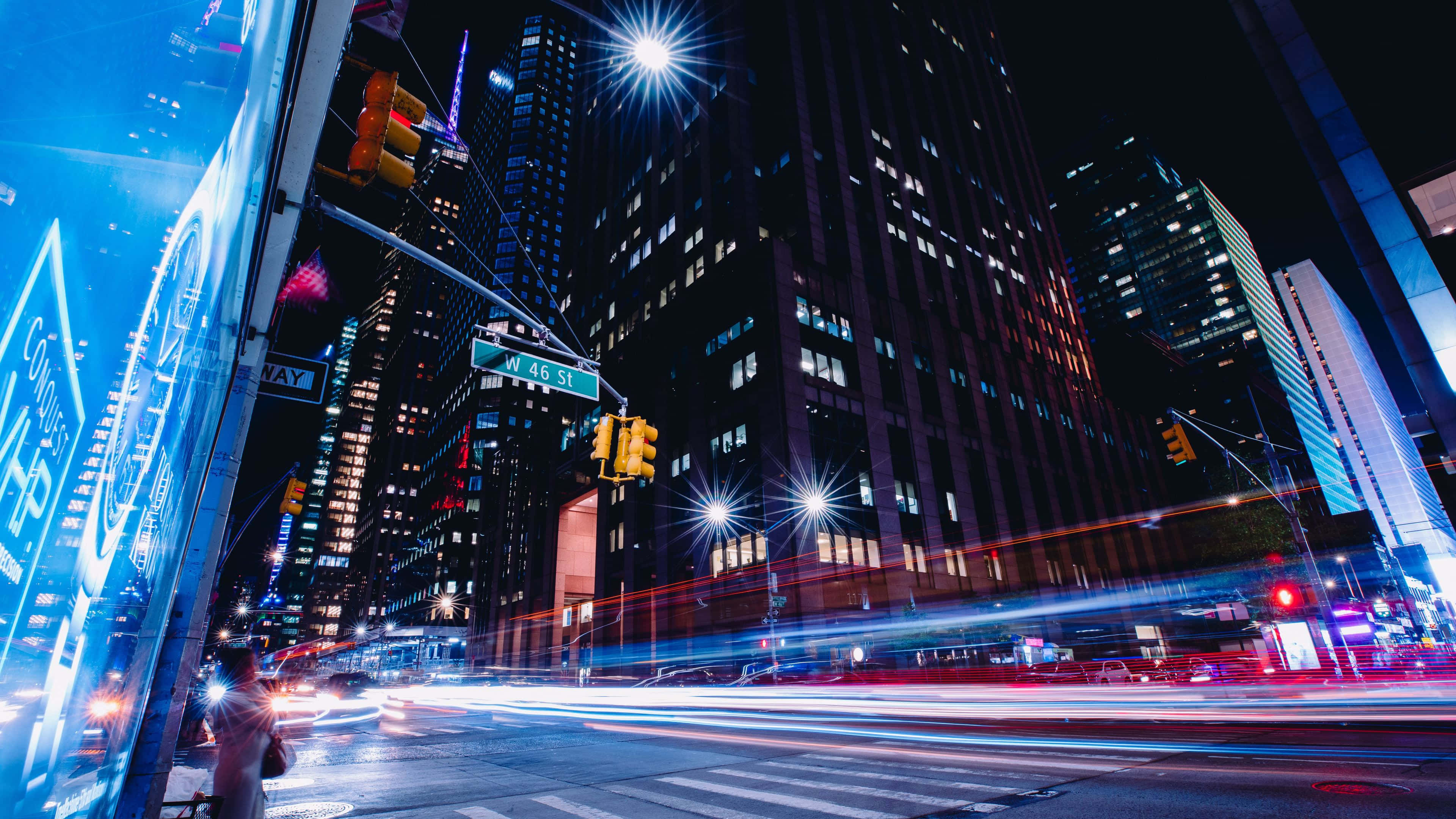 City Street 桌布 壁紙 — 充滿活力的夜景，車流形成的光跡和摩天大樓在星形街燈下閃耀。