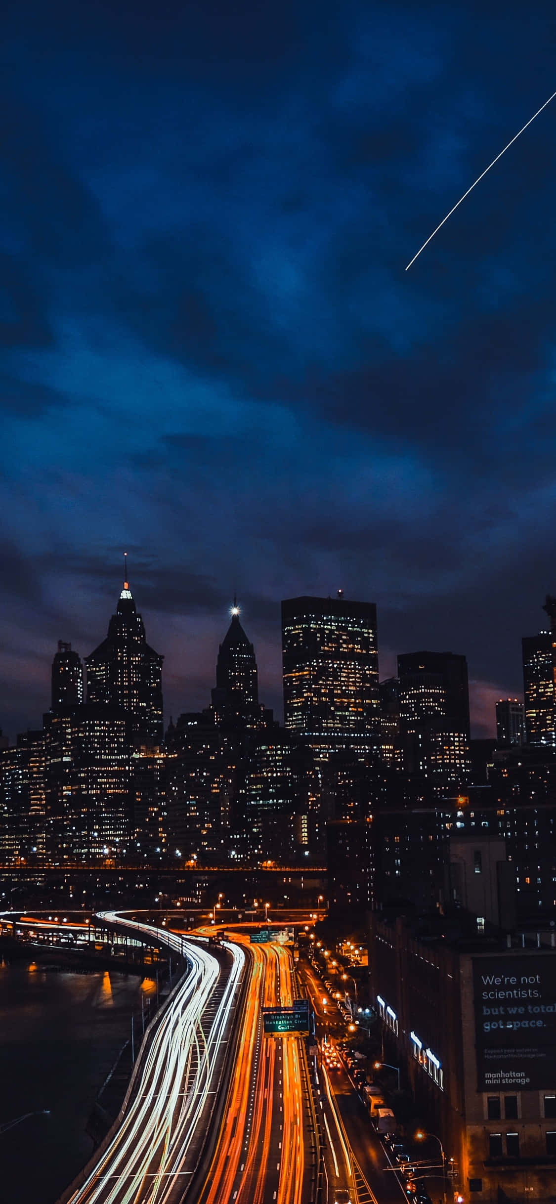 New York 桌布 壁紙 — 充滿活力的夜景，閃爍的摩天大樓和車流的光軌，在深藍色的天空下有一條明亮的流星軌跡。