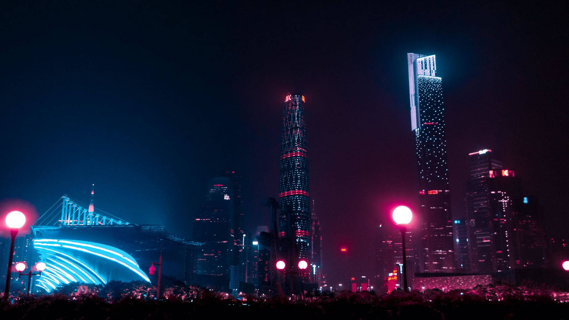 夜晚的城市天際線，有明亮的摩天大樓和發光的街燈。 — 黑暗城市 壁紙