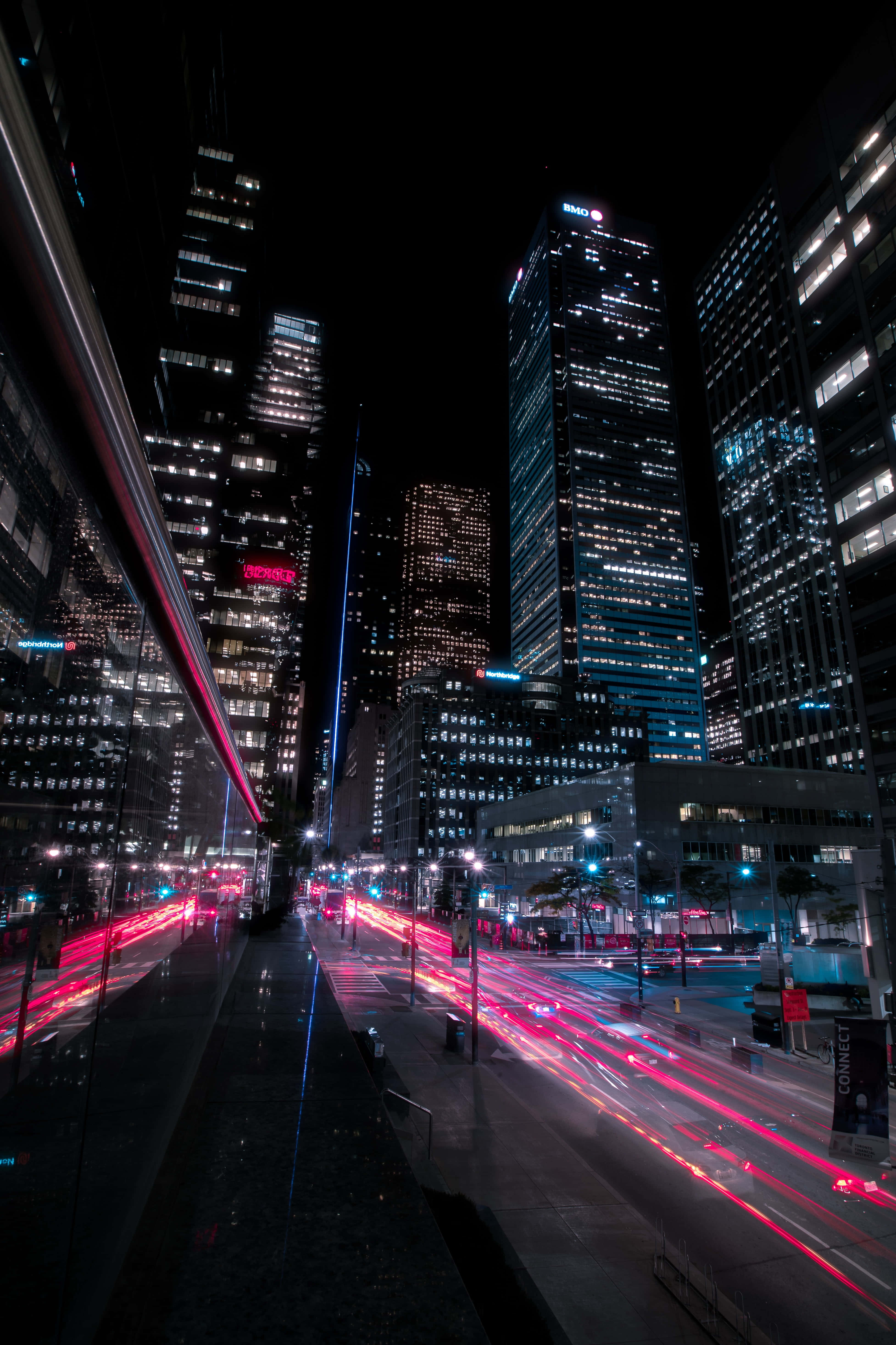 Street 桌布 壁紙 — 充滿活力的夜景，高聳的摩天大樓和紅色車燈照亮濕漉漉的街道。