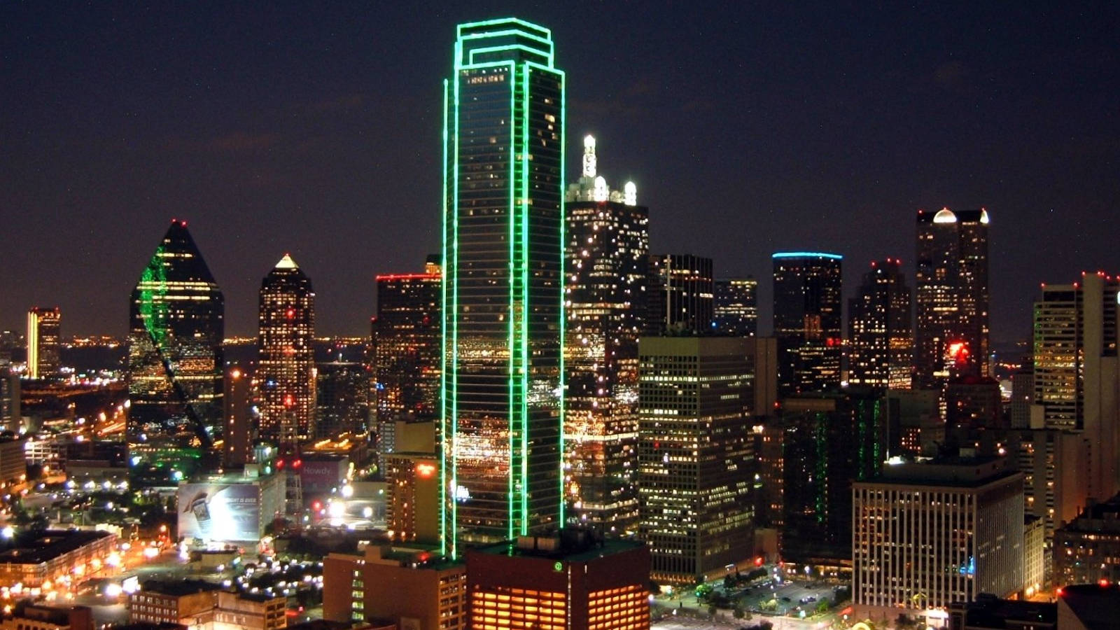 Oklahoma 桌布 壁紙 — 充滿活力的夜景城市景觀，一座高聳的摩天大樓在黑暗的天空中勾勒出明亮的綠色霓虹燈光。