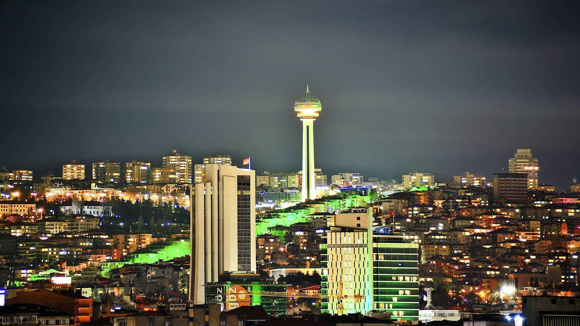 Ankara 桌布 壁紙 — 充滿活力的夜景城市景觀，以發光的綠色塔樓和黑暗天空下燈火通明的建築為特色。