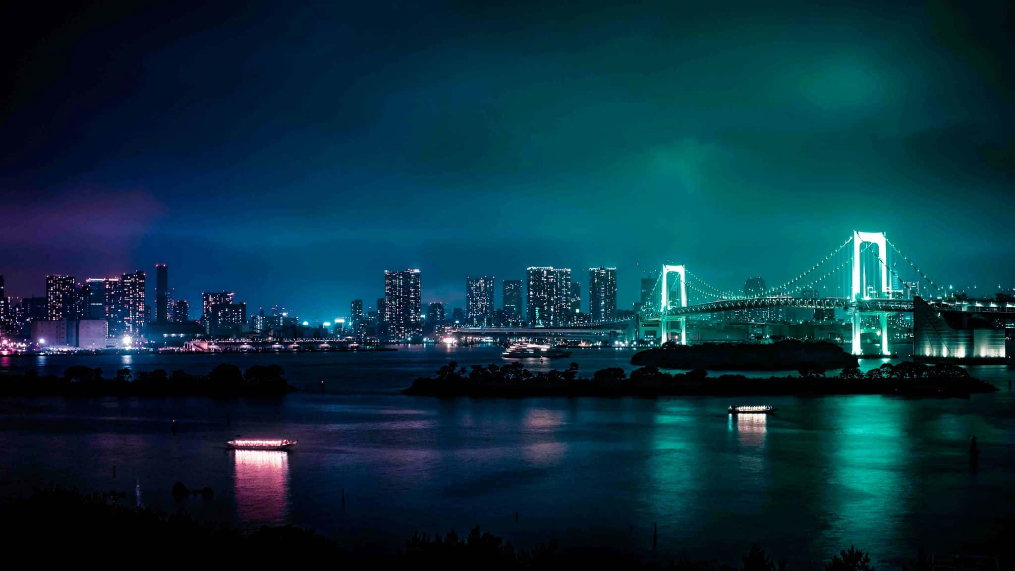 2048x1152 Aesthetic 桌布 壁紙 — 充滿活力的夜景城市景觀，彩虹橋在水面上亮起，發光的摩天大樓和船隻反射著霓虹燈光。
