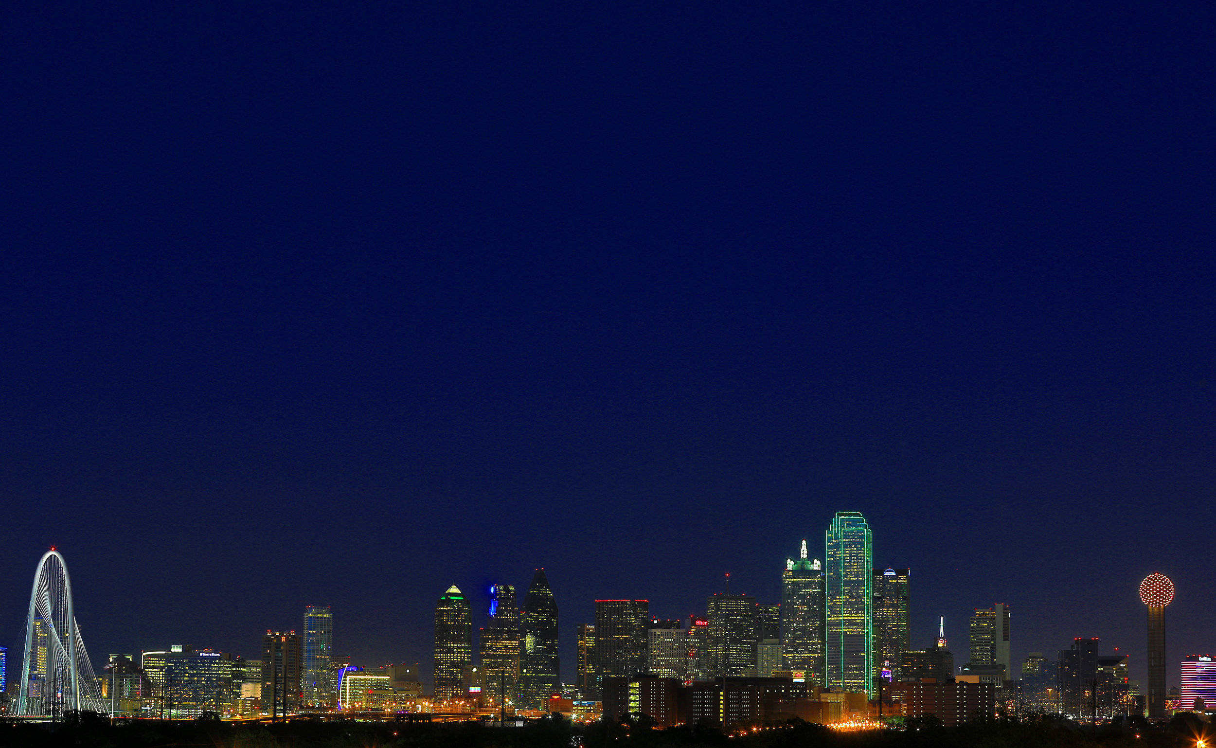 城市 桌布 壁紙 — 充滿活力的夜景城市景觀，摩天大樓燈火通明，摩天輪在深藍色天空下閃閃發光。
