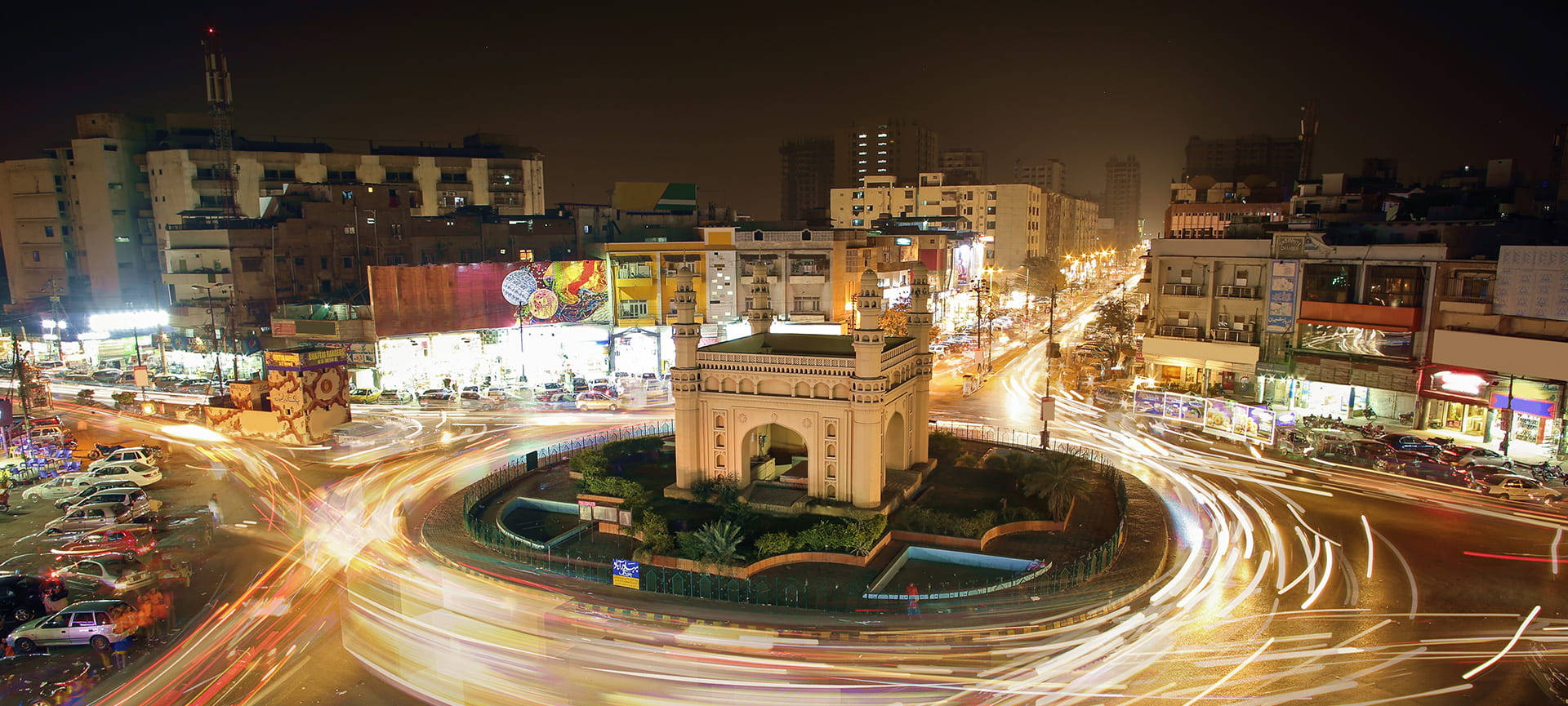 Karachi 桌布 壁紙 — 充滿活力的夜景城市景觀，歷史拱門被繁忙城市圓環的車流漩渦光跡環繞。